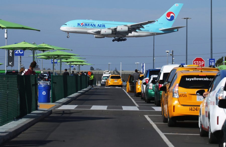 A Korean Air plane lands as taxis are lined up at the new 'LAX-it' ride-hail passenger pickup lot at Los Angeles International Airport on Nov. 6, 2019. (Credit: Mario Tama/Getty Images)