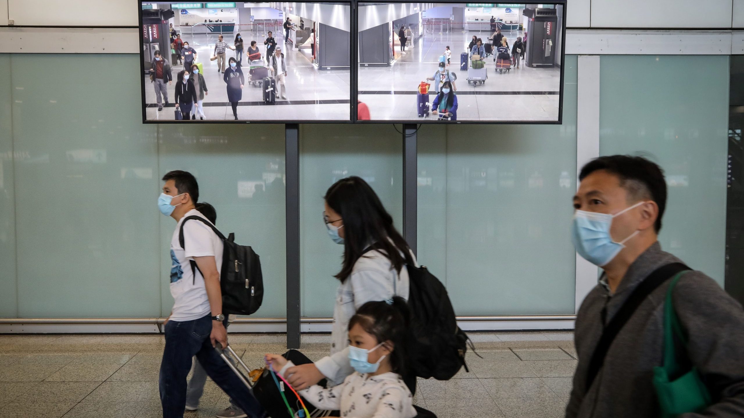 Travelers wearing face masks as a precautionary measure walk in the arrivals area at Hong Kong International Airport ahead of the Chinese New Year in Hong Kong on Jan. 23, 2020. (Credit: VIVEK PRAKASH/AFP via Getty Images)