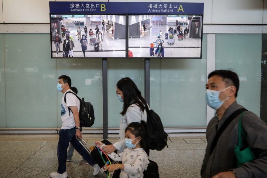 Travelers wearing face masks as a precautionary measure walk in the arrivals area at Hong Kong International Airport ahead of the Chinese New Year in Hong Kong on Jan. 23, 2020. (Credit: VIVEK PRAKASH/AFP via Getty Images)