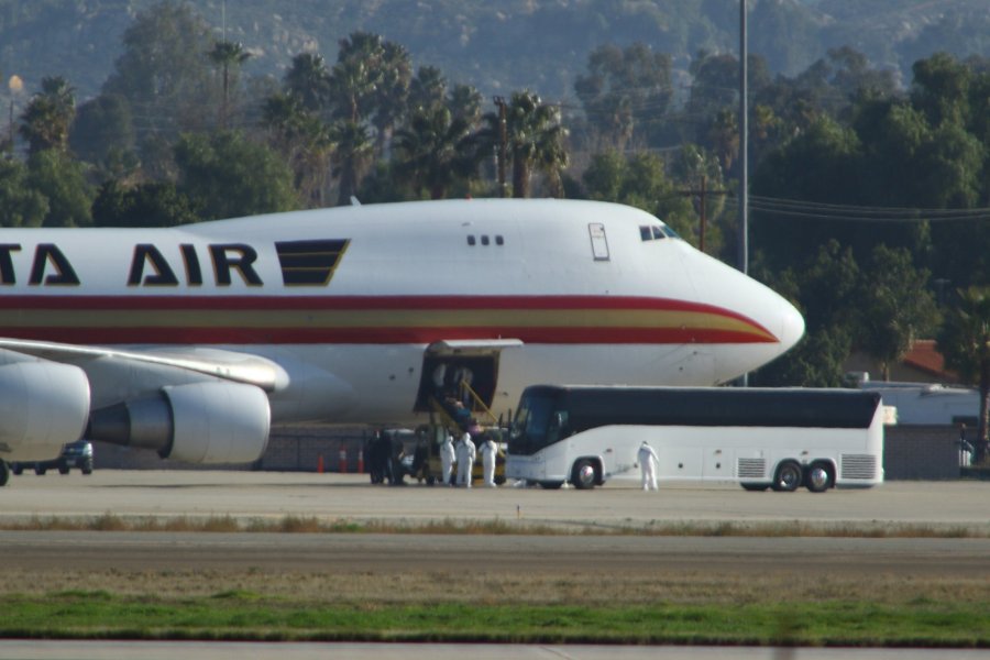 Personnel in biological hazard suits welcome passengers evacuated from Wuhan, the Chinese city at the heart of a growing outbreak of the deadly 2019 Novel Coronavirus shortly after the plane landed at March Air Reserve Base in Riverside County on Jan. 29, 2020. (Credit: MATT HARTMAN/AFP via Getty Images)