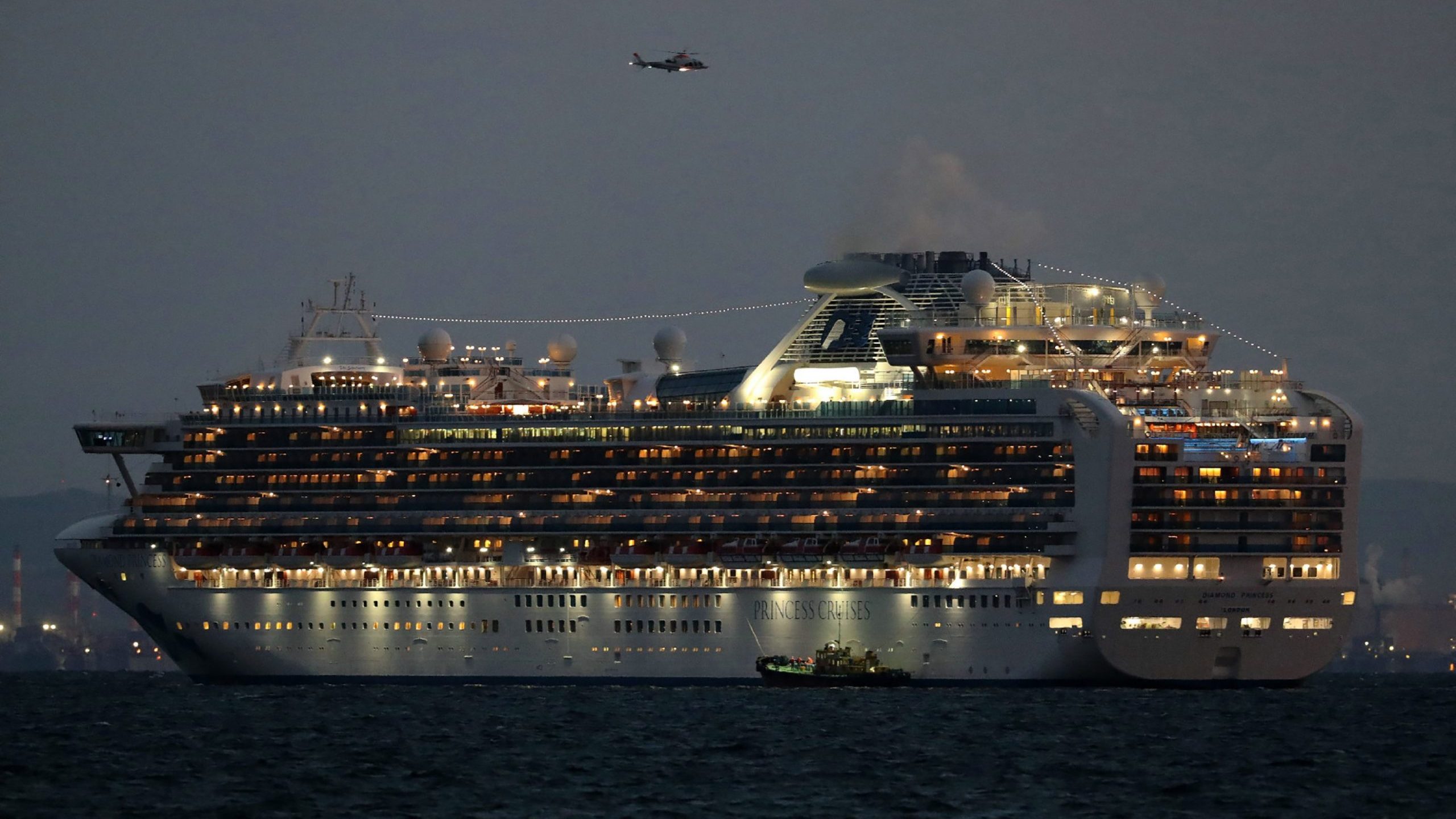 A small boat is pictured next to the Diamond Princess cruise ship with over 3,000 people as it sits anchored in quarantine off the port of Yokohama on Feb. 4, 2020, a day after it arrived with passengers feeling ill. (Credit: STR/JIJI PRESS/AFP via Getty Images)