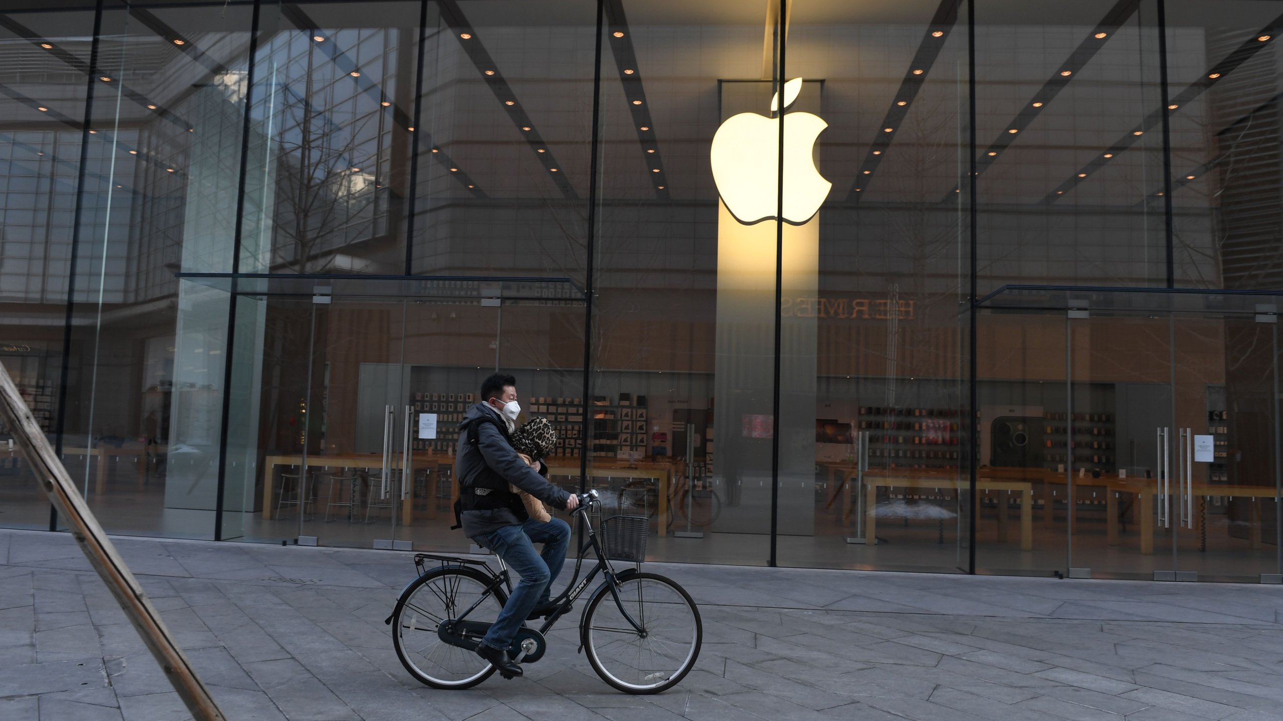 A man cycles past a closed Apple store in Beijing on Feb. 8, 2020. (Credit: GREG BAKER/AFP via Getty Images)