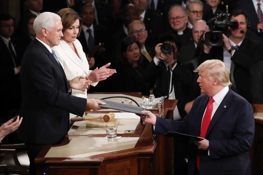 President Donald Trump hands Vice President Mike Pence a copy of his State of the Union speech before the address on Feb. 4, 2020. (Credit: Drew Angerer / Getty Images)