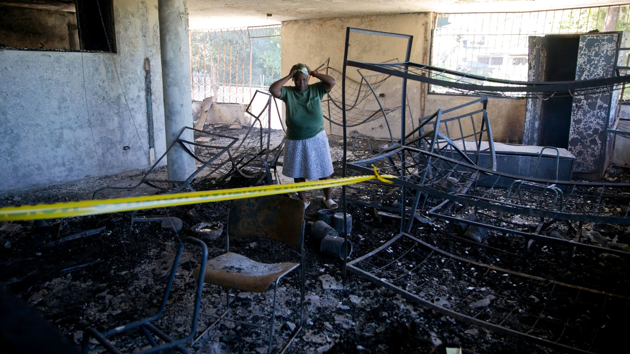 Rose-Marie Louis, a staff worker at the Orphanage of the Church of Bible Understanding, holds her head amid the charred children's home, including the unrecognizable body of a child marked by a yellow piece of paper, bottom right, in Kenscoff, on the outskirts of Port-au-Prince, Haiti, Friday, Feb. 14, 2020. (Credit: AP Photo/Dieu Nalio Chery/via CNN)