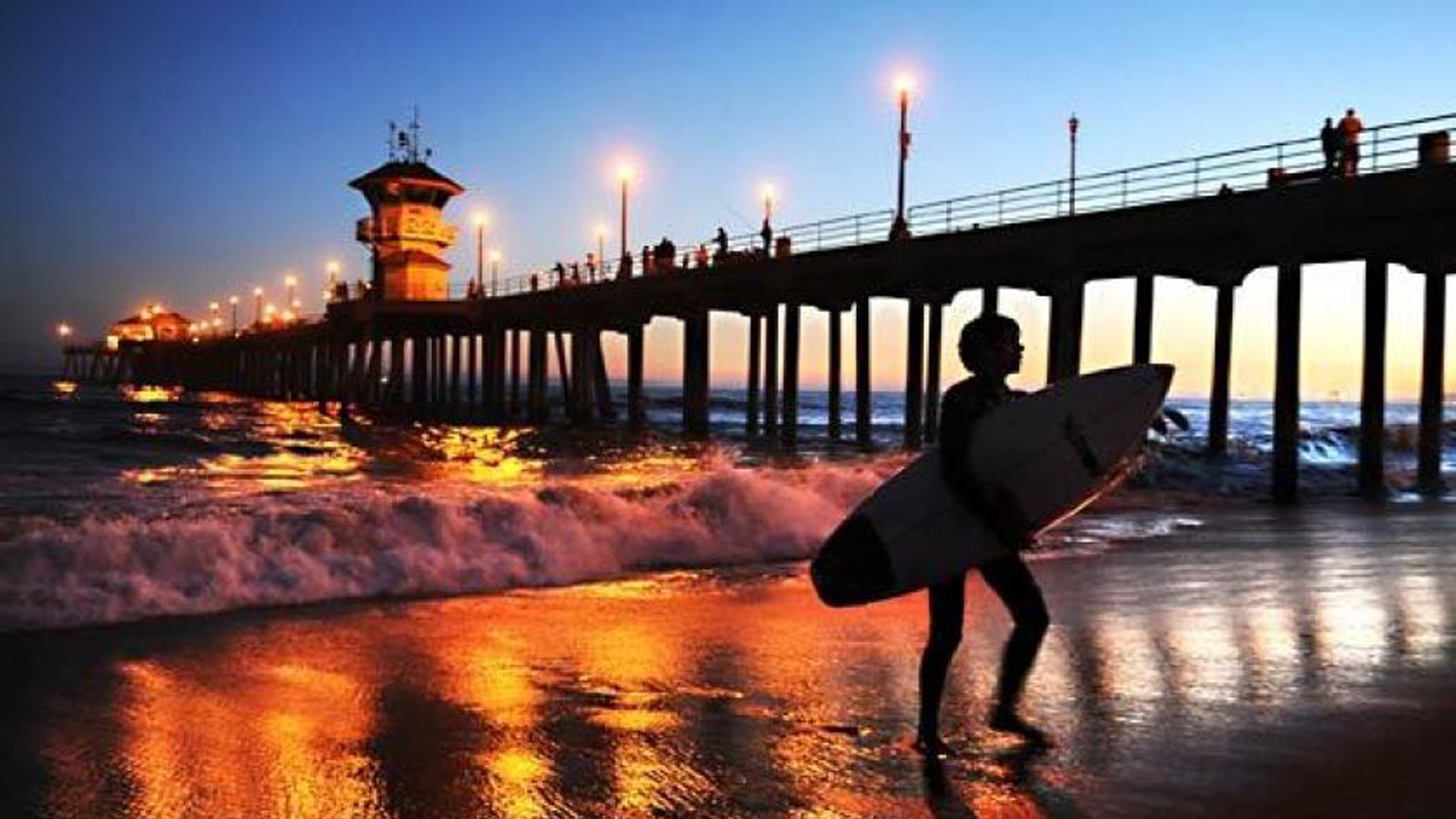 A surfer leaves the water at Huntington Beach Pier. Early Friday, a tsunami alarm sounded across the city, but officials said it was made in error.(Credit: Wally Skalij / Los Angeles Times)