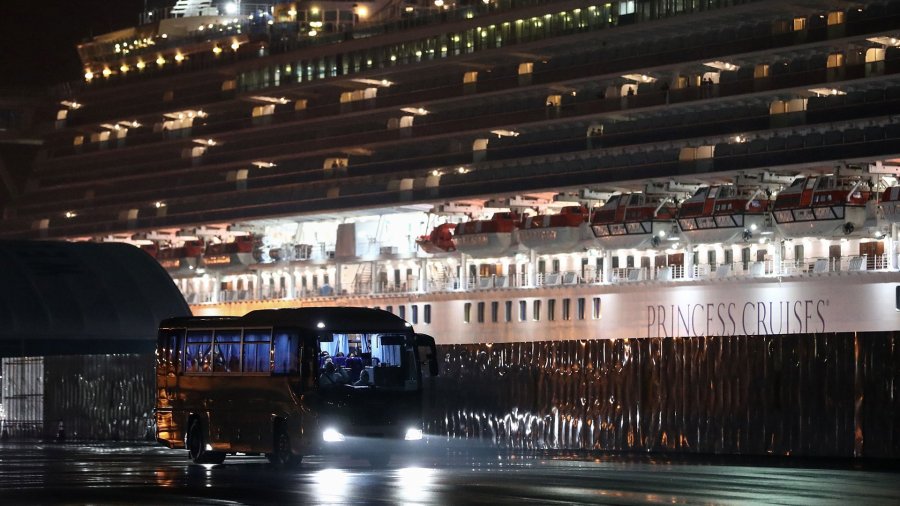 A bus carrying U.S. citizens leaves the Daikaku Pier Cruise Terminal in Yokohama port, next to the Diamond Princess cruise ship, with people quarantined onboard due to fears of the new COVID-19 coronavirus, on Feb. 17, 2020. (Credit: Behrouz Mehri/AFP/Getty Images)