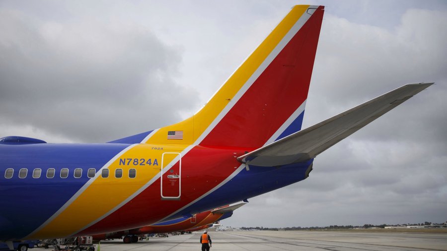 A Southwest Airlines Co. employee walks underneath the tail of a Boeing Co. 737 aircraft on the tarmac at John Wayne Airport (SNA) in Santa Ana, California, U.S., on Thursday, April 14, 2016. (Credit: Patrick T. Fallon/Bloomberg via Getty Images)