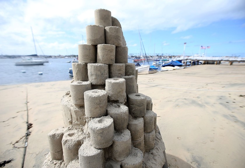 A toilet paper tower titled “Roll With It” by sandcastle artist Chris Crosson rises on Balboa Island in Newport Beach.(Don Leach / Times Community News)