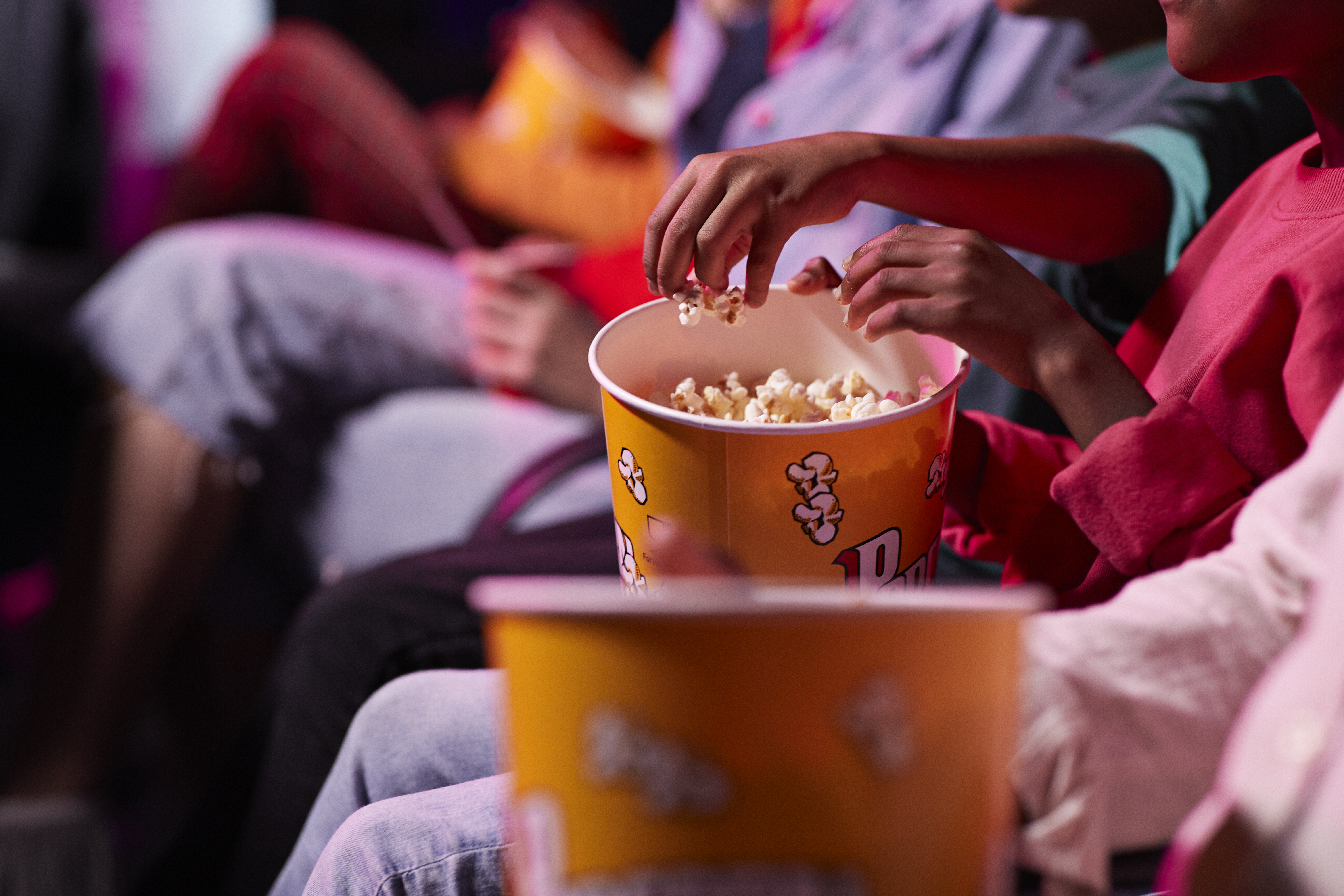 Friends share popcorn in a theater. (Getty Images)