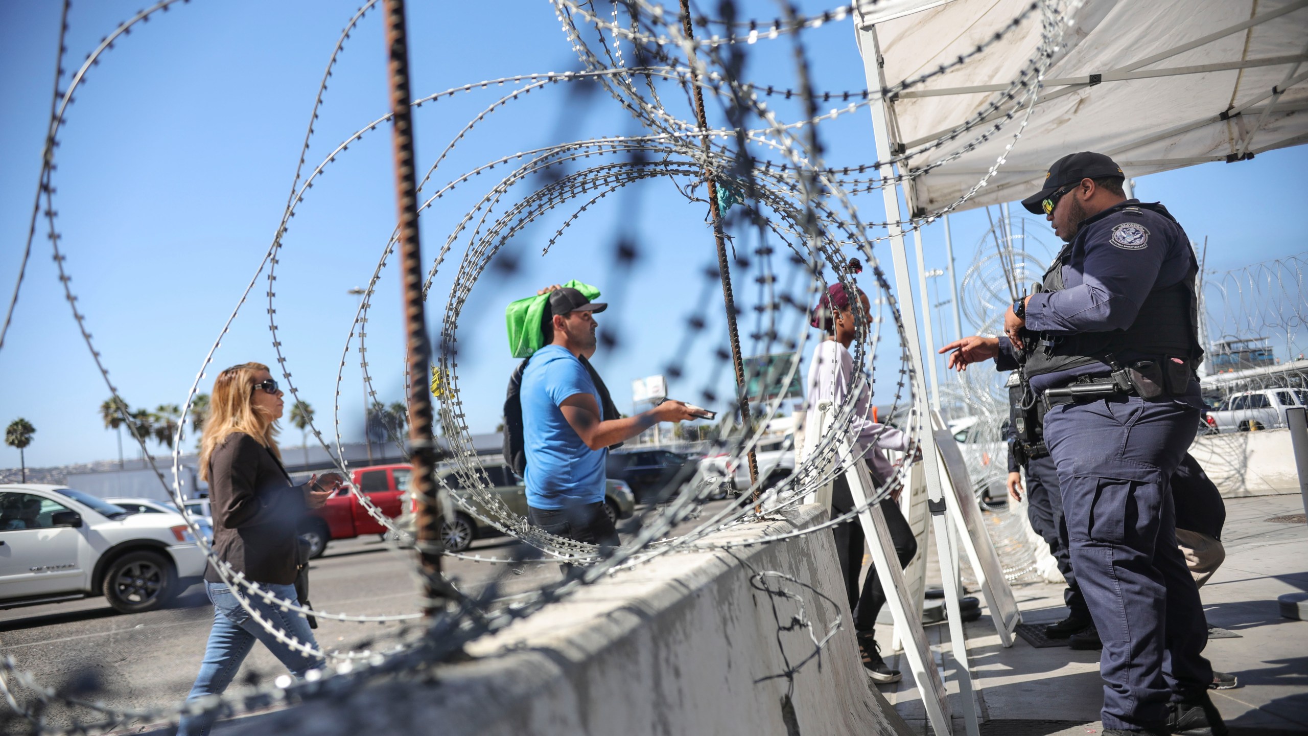 An immigration agent checks pedestrians' documentation at the San Ysidro Port of Entry on Oct. 2, 2019. (Credit: Sandy Huffaker / AFP / Getty Images)