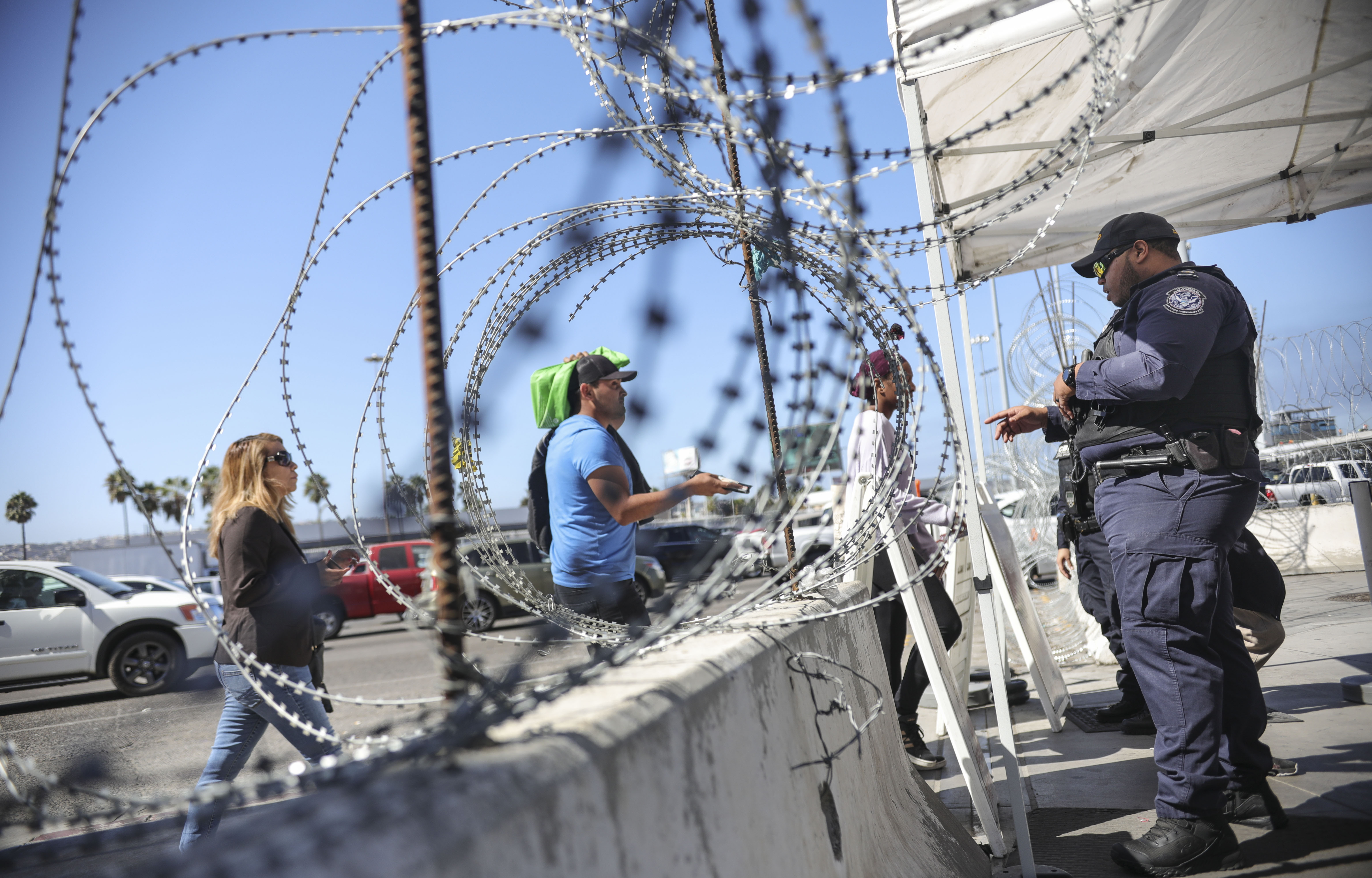 An immigration agent checks pedestrians' documentation at the San Ysidro Port of Entry on Oct. 2, 2019. (Credit: Sandy Huffaker / AFP / Getty Images)