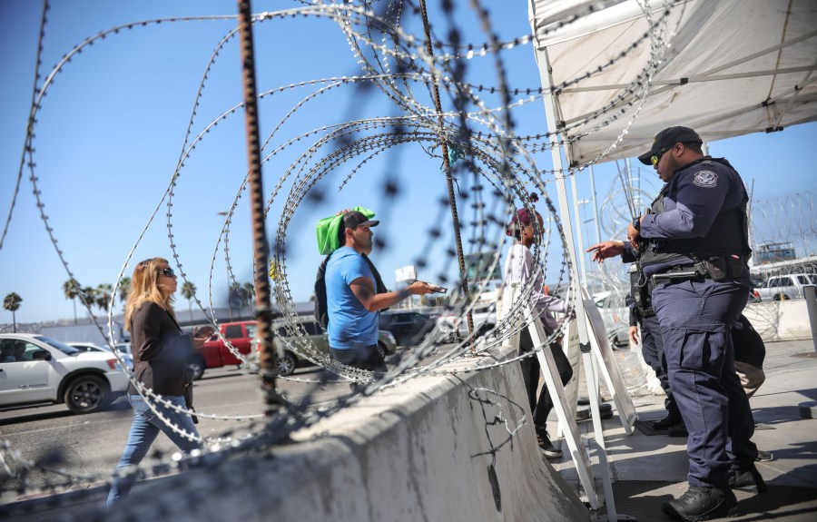 An immigration agent checks pedestrians' documentation at the San Ysidro Port of Entry on Oct. 2, 2019. (Credit: Sandy Huffaker / AFP / Getty Images)