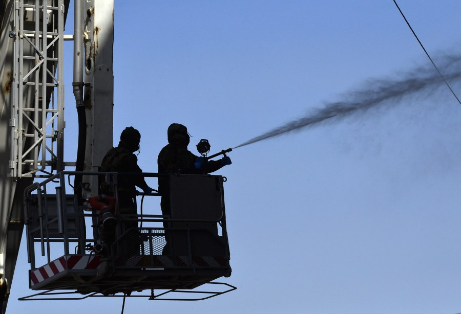 Members of the Iraqi civil defense spray disinfectant on and around a building where Islamic students are quarantined for having had contact with Iraq's first confirmed case of novel coronavirus infection, in the central holy city of Najaf, on Feb. 26, 2020. (Haidar HAMDANI / AFP) (Photo by HAIDAR HAMDANI/AFP via Getty Images)