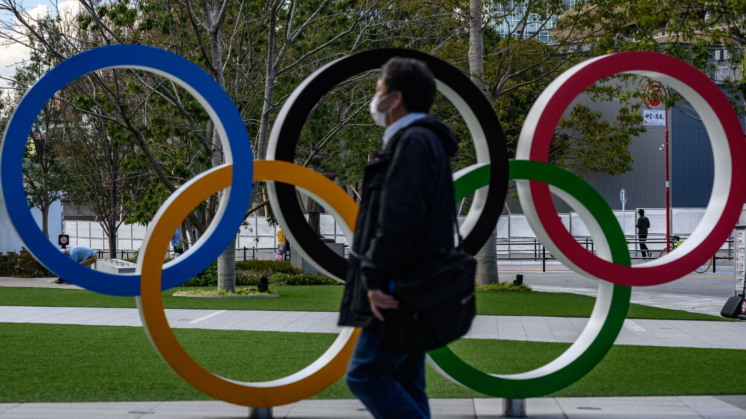 A man wearing a face mask walks in front of the Olympic Rings in Tokyo on March 11, 2020. (Philip Fong/AFP via Getty Images)