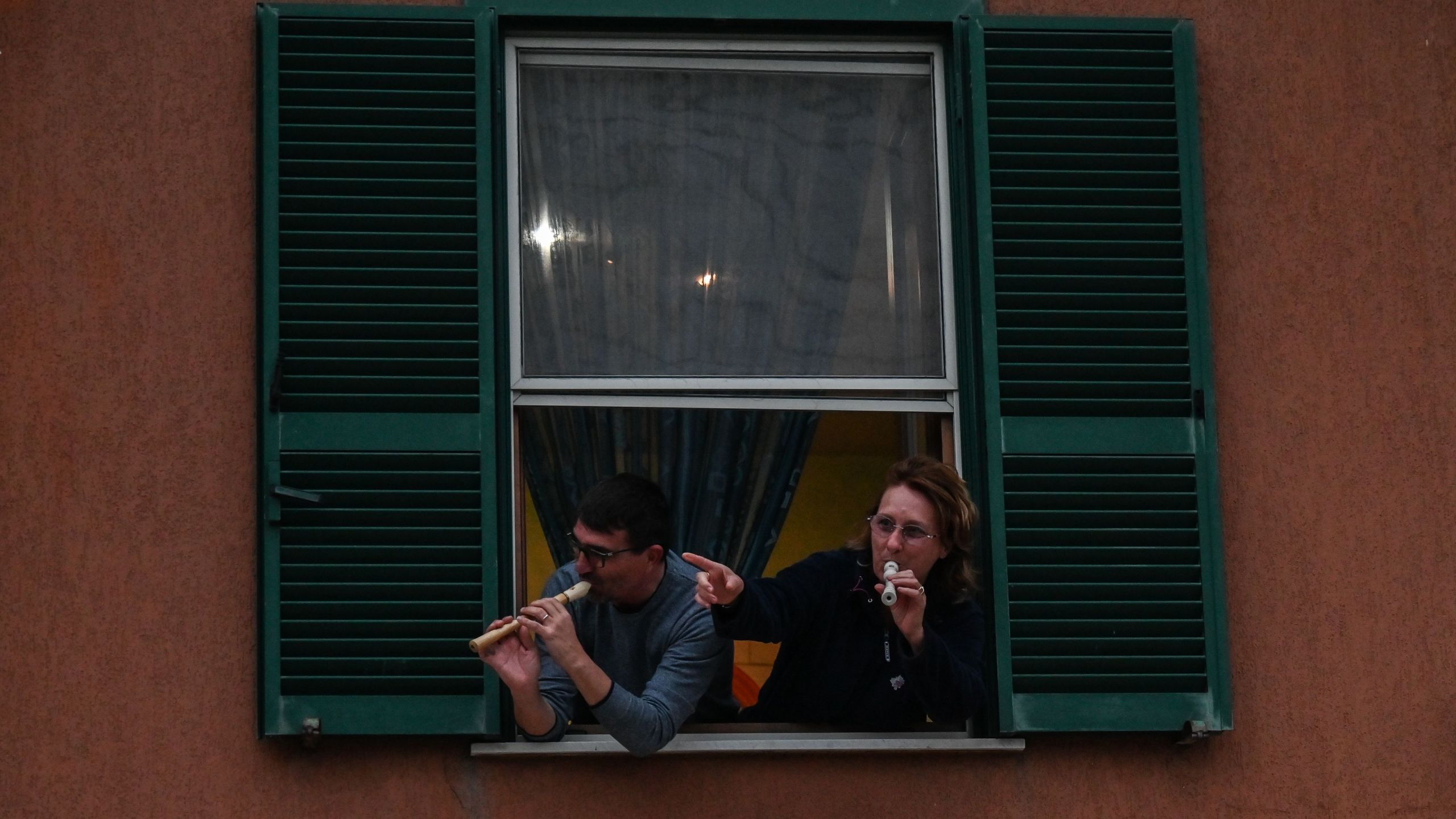 People play the Italian national anthem with from the window of their house in Rome during a music flash mob aimed at livening up the city's silence during the coronavirus lockdown, on March 13, 2020. (Credit: Andreas Solaro / AFP / Getty Images)