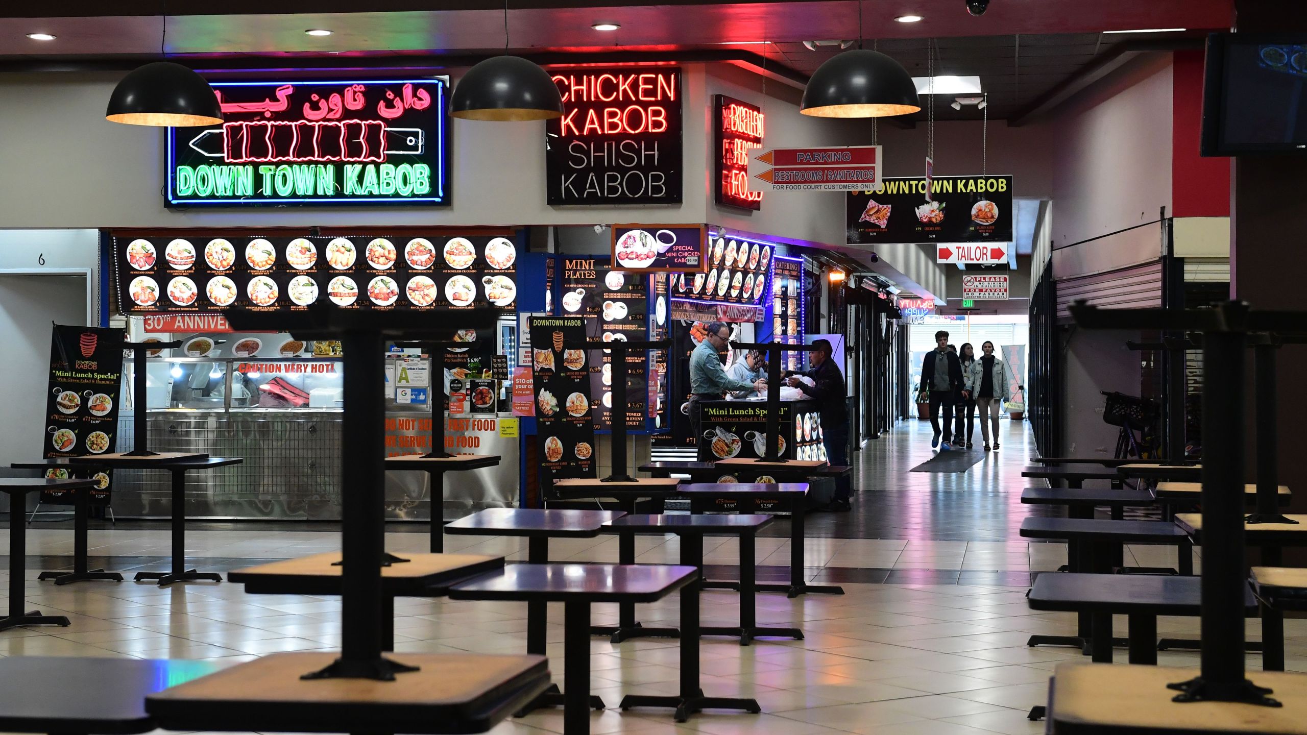 Patrons arrive at a closed food court in Los Angeles where tables are placed on top of tables but takeout orders are available on March 17, 2020, as the coronavirus epidemic leads to restaurant and school closures. (Credit: Frederic J. Brown / AFP / Getty Images)