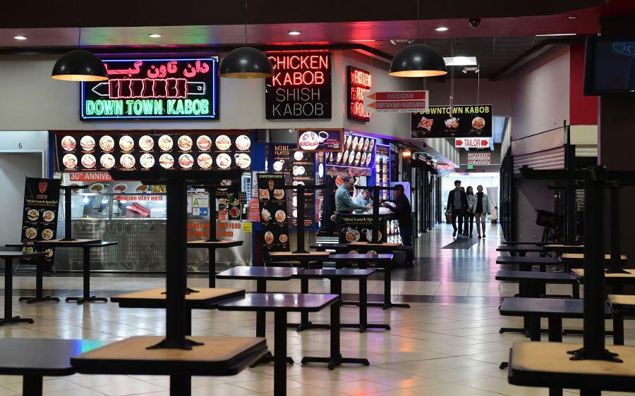 Patrons arrive at a closed food court in Los Angeles where tables are placed on top of tables but takeout orders are available on March 17, 2020, as the coronavirus epidemic leads to restaurant and school closures. (Credit: Frederic J. Brown / AFP / Getty Images)