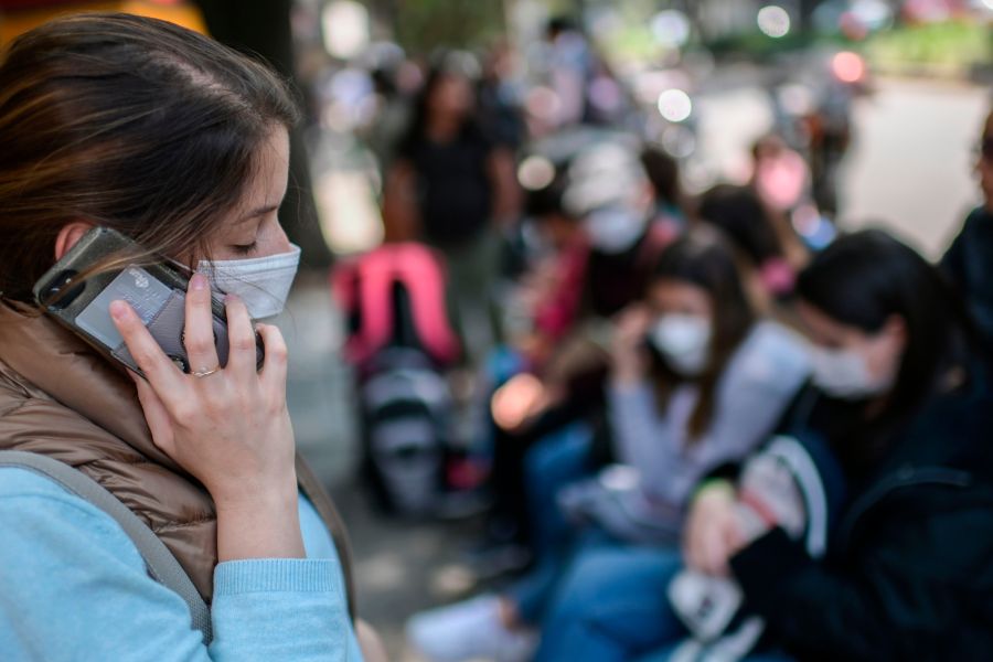 A woman wearing a face mask speaks on her mobile phone as she waits outside the consulate of Peru in Mexico City, on March 18, 2020. (Pedro Pardo/AFP via Getty Images)