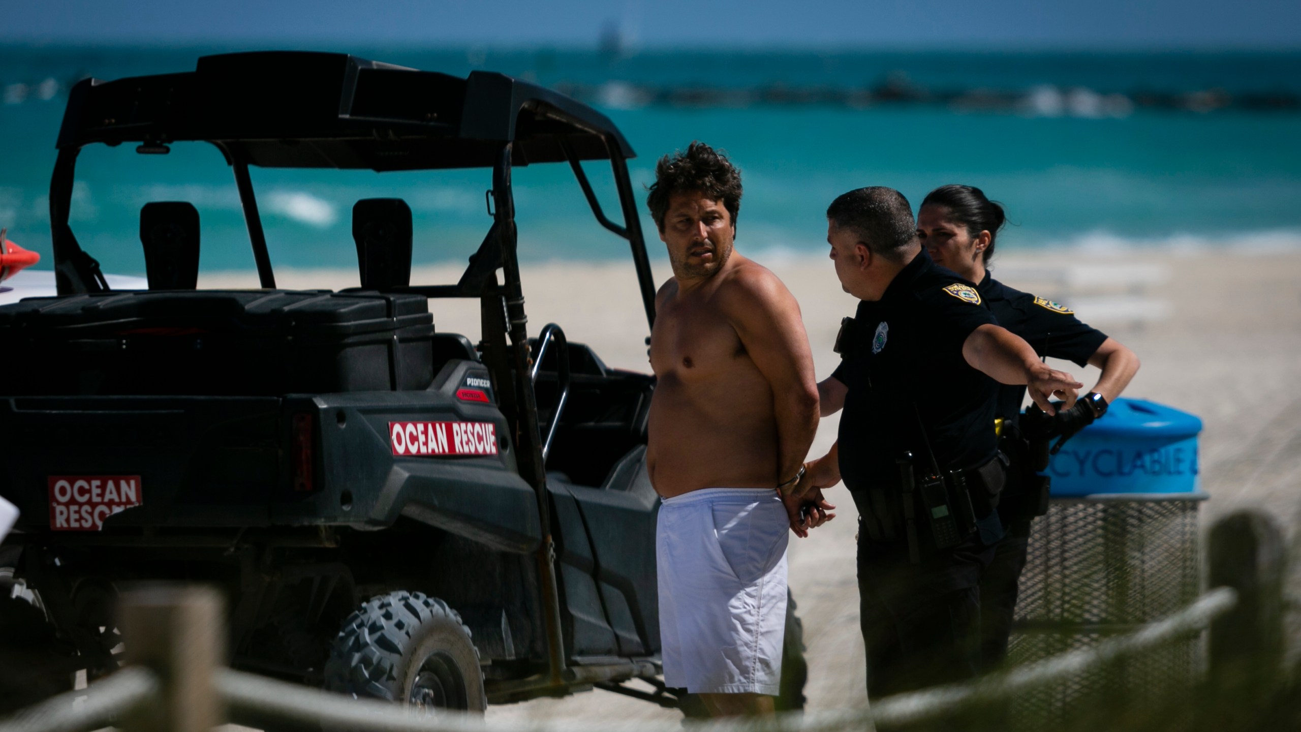 Police officers detain a man who allegedly trespassed into a closed beach at South Beach, Fla., on March 19, 2020. - In response to the virus's spread, Miami Beach and Fort Lauderdale are closing down parts of their public beaches and limiting the hours of operations for bars, clubs and restaurants to stifle the spread of coronavirus. (Eva Marie UZCATEGUI / AFP via Getty Images)