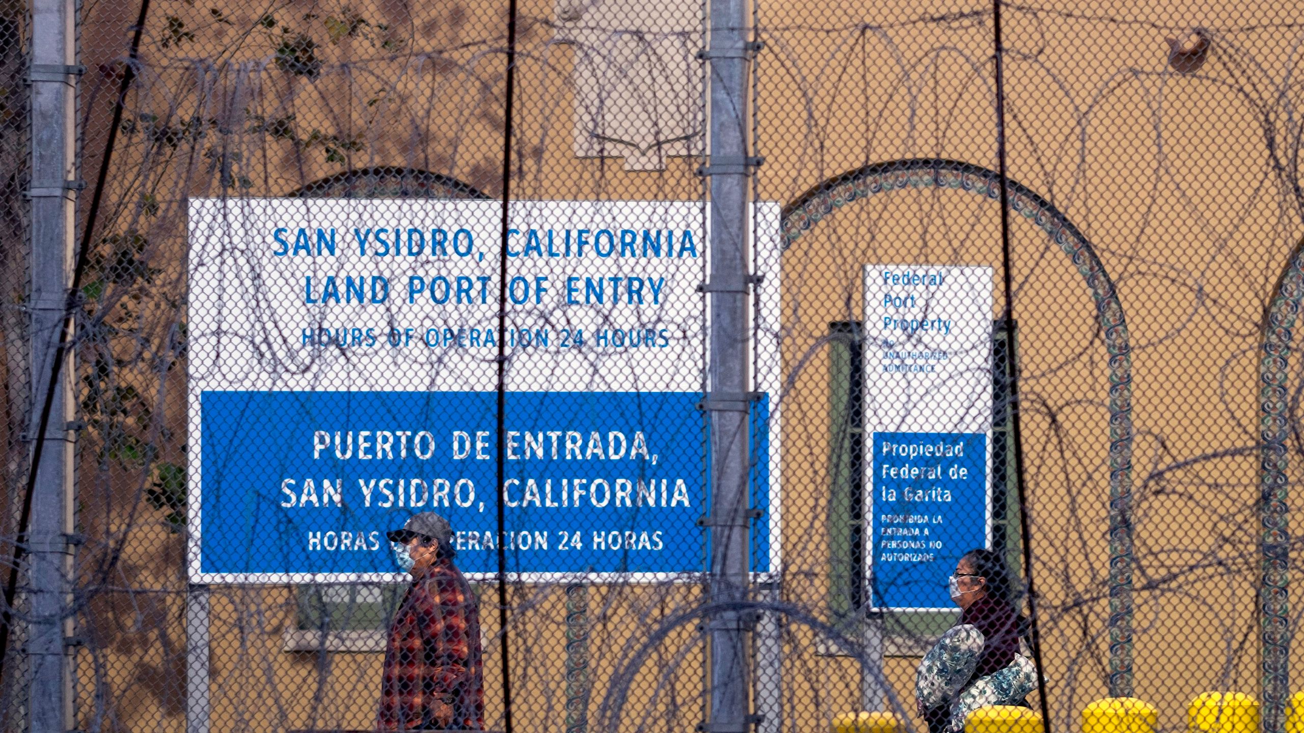 People wear face masks as they walk at San Ysidro port of entry on the Mexico-U.S. border as seen from Tijuana on March 21, 2020. (Guillermo Arias/ AFP / Getty Images)