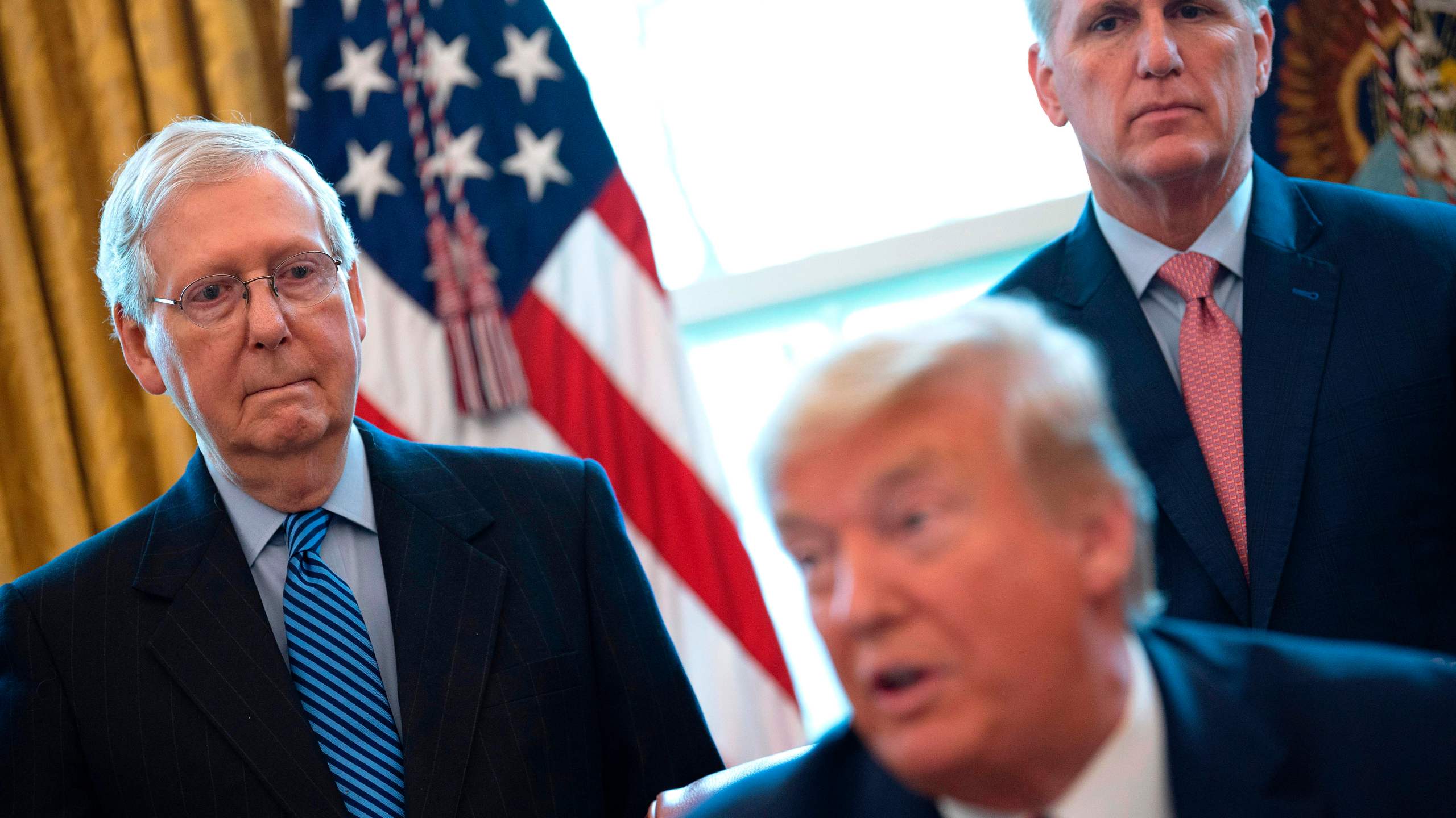 U.S. Senate Majority Leader Mitch McConnell (L) and House Minority Leader Kevin McCarthy (R) look on as U.S. President Donald Trump speaks before signing the CARES act, a $2 trillion rescue package to provide economic relief amid the coronavirus outbreak, at the Oval Office of the White House on March 27, 2020. (JIM WATSON/AFP via Getty Images)