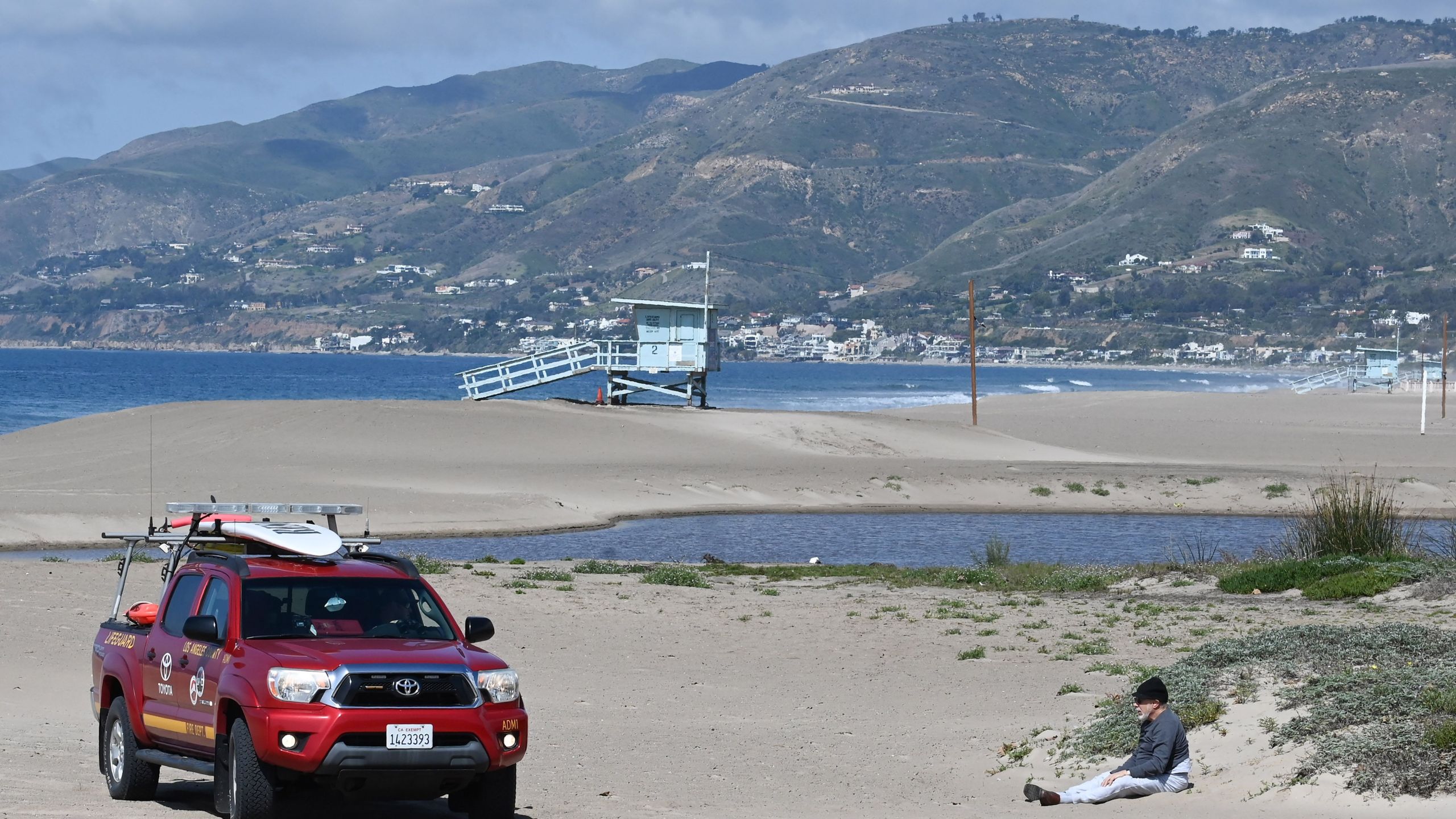 A Los Angeles County Fire Department lifeguard tells a man that he can not sit on the beach, at Zuma Beach in Malibu on March 28, 2020, after all L.A. County beaches were closed in an effort to stem the spread of COVID-19. (Robyn Beck/AFP via Getty Images)