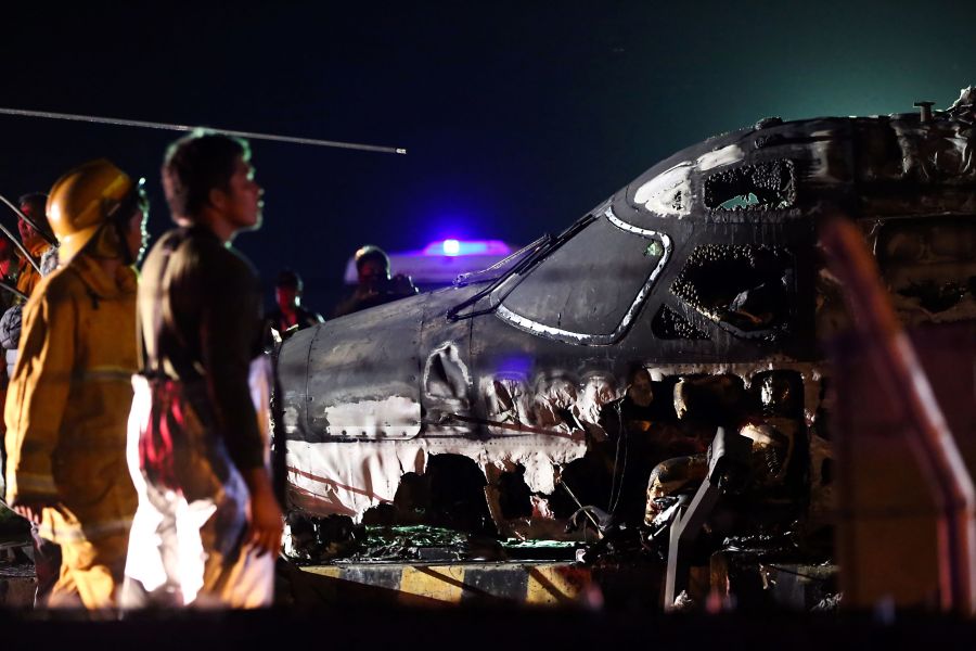 Rescuers stand next to the wreckage of a Westwind aircraft after it caught fire during takeoff at Manila International Airport in Manila on March 29, 2020. (AFP via Getty Images)