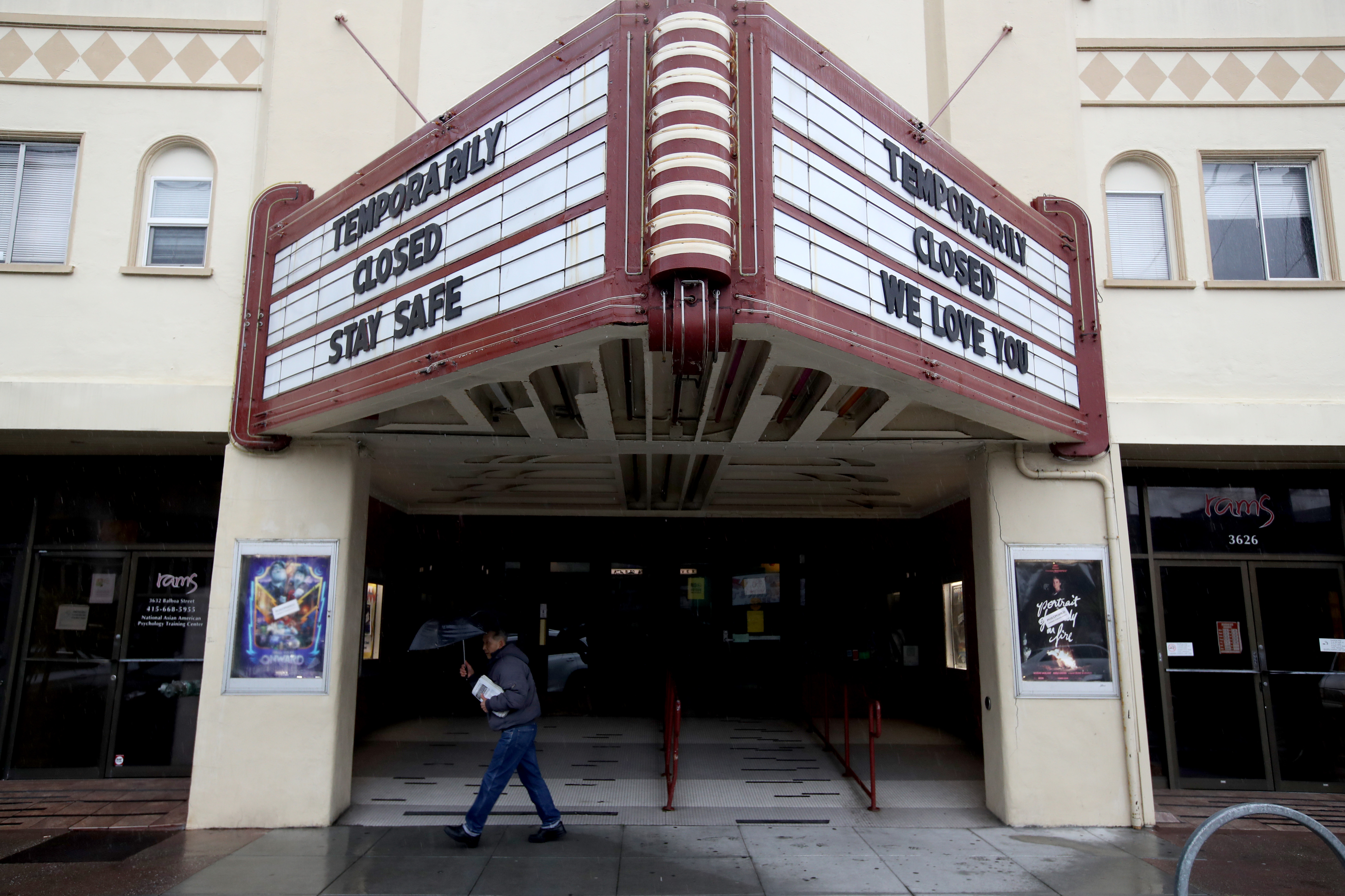 A pedestrian walks under the marquee at Balboa Theater that notes the theater is closed until further notice due to a statewide ordinance banning gatherings of more than 250 people on March 15, 2020 in San Francisco. (Justin Sullivan / Getty Images)