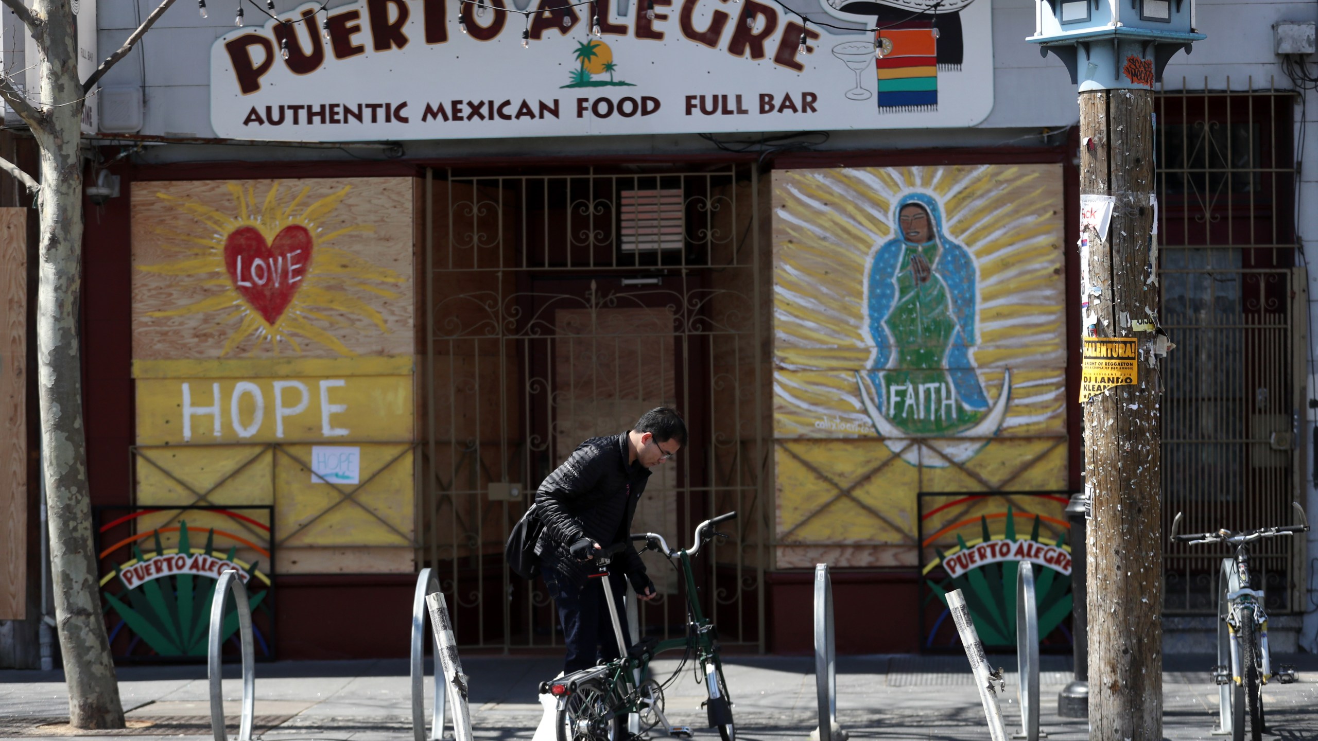 A cyclist parks his bicycle in front of a business that has the windows covered with plywood on Valencia Street on March 20, 2020 in San Francisco. (Justin Sullivan/Getty Images)