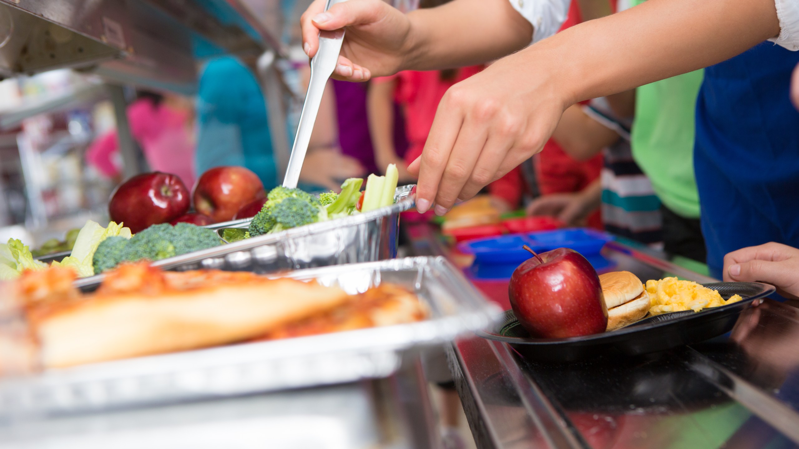 A cafeteria worker helps elementary students select food in a lunch line (Getty Images)