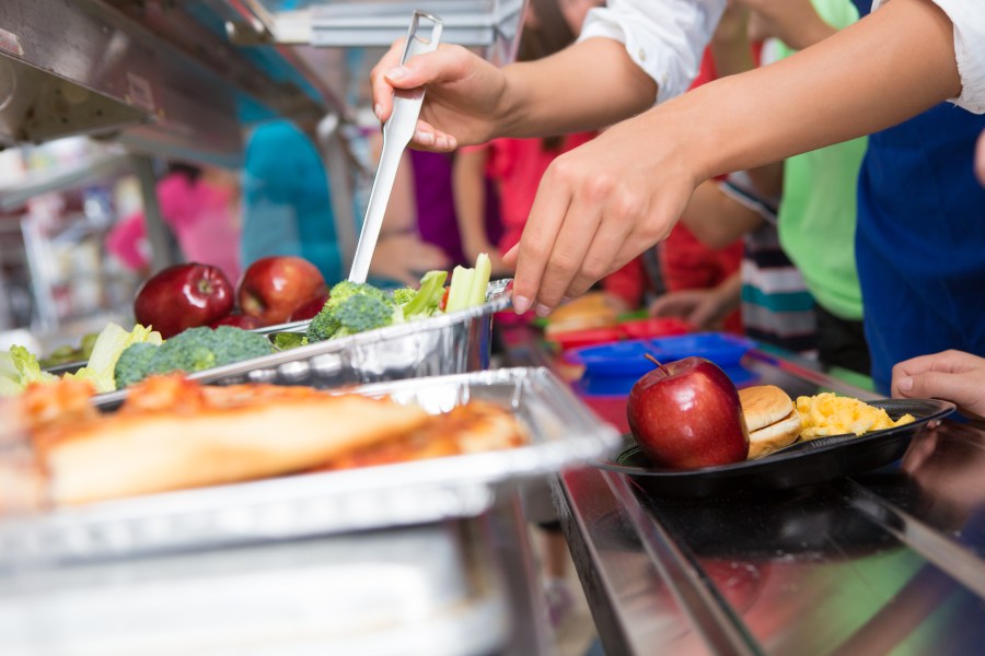 A cafeteria worker helps elementary students select food in a lunch line (Getty Images)