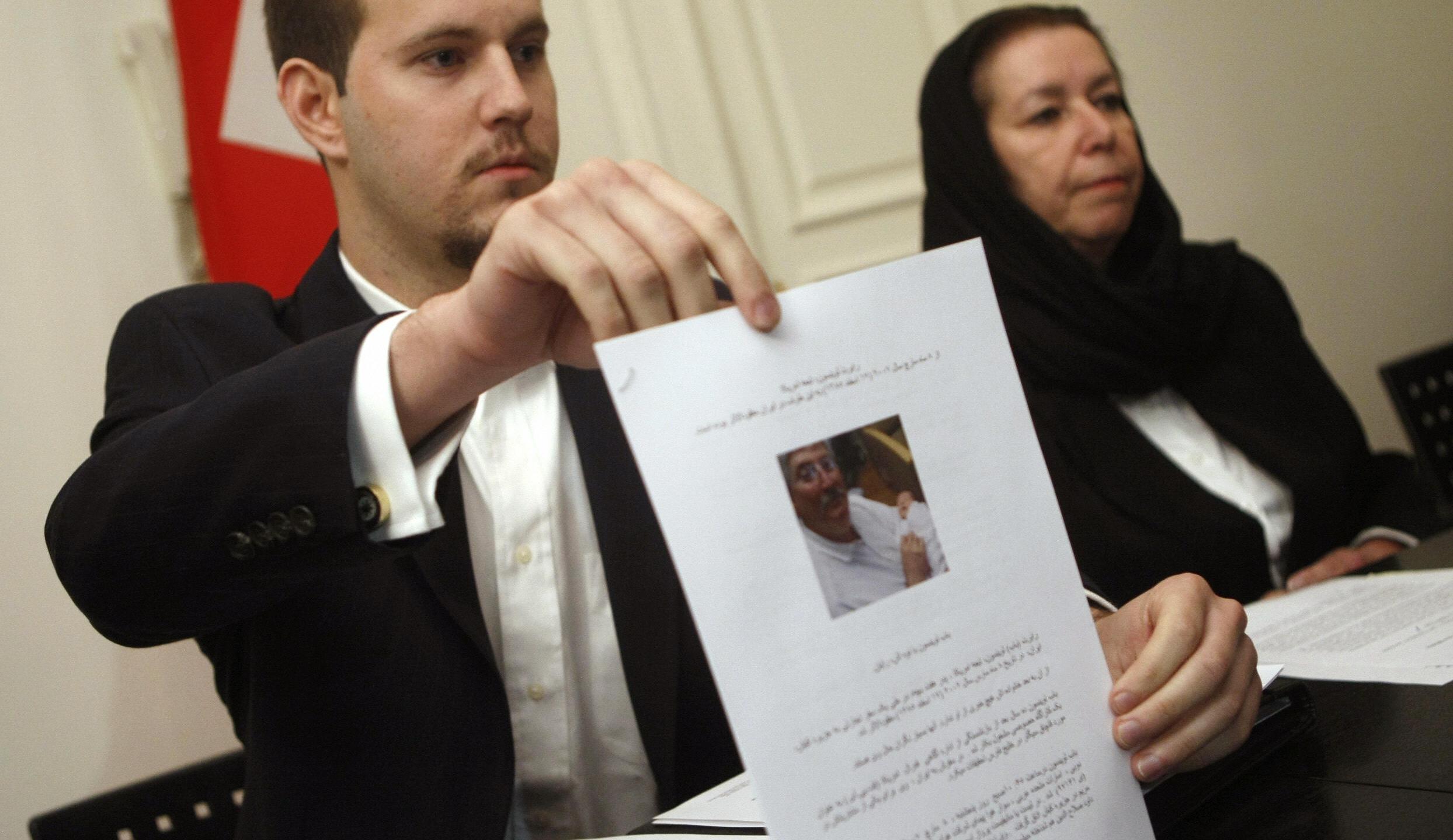 Daniel Levinson (left) shows a picture of his father, ex-FBI agent Robert Levinson, holding his grandson Ryan during a press conference with his mother Christine at the Swiss embassy in Tehran on Dec. 22 2007. (BEHROUZ MEHRI/AFP via Getty Images)