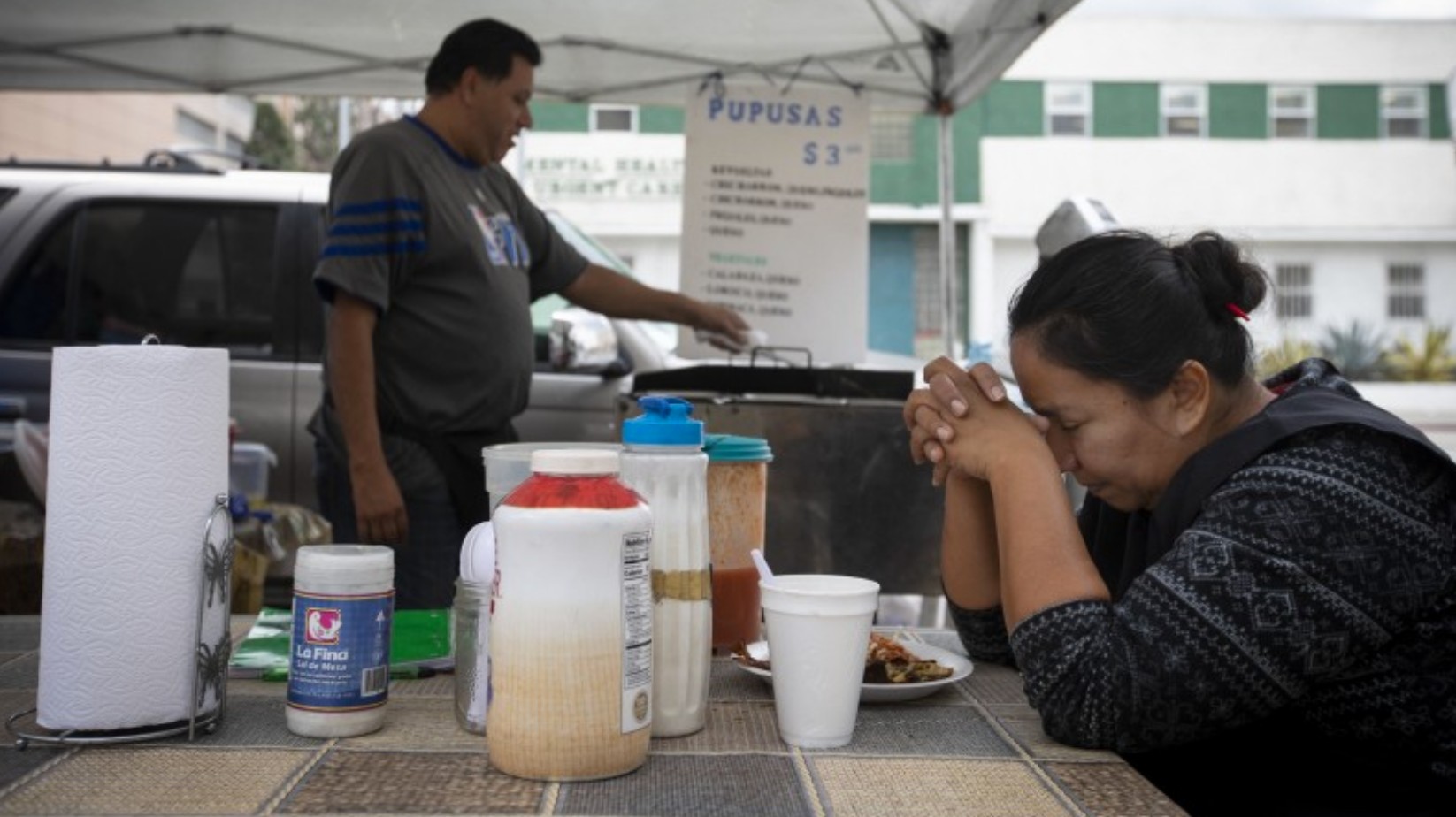 Patricia Escobar prays before having her lunch she bought from a vendor outside County-USC Medical Center on March 17, 2020. (Francine Orr/Los Angeles Times)