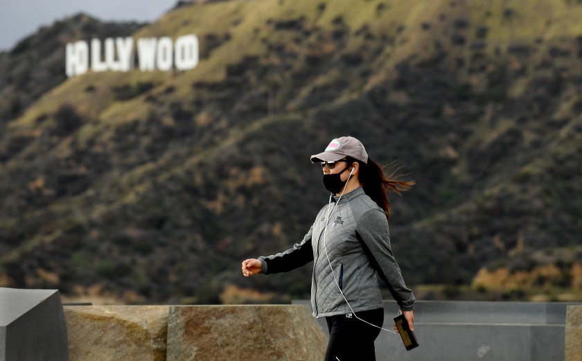 A hiker wears a mask during a walk past the Hollywood sign in Griffith Park on March 23, 2020.(Wally Skalij / Los Angeles Times)