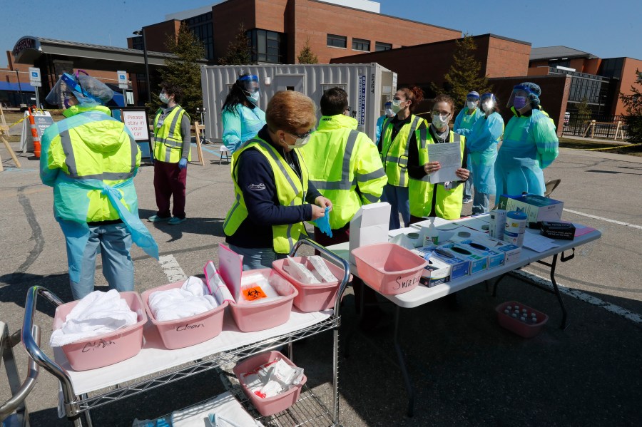 Healthcare workers prepare their supplies at a COVID-19 drive-thru testing site at Henry Ford West Bloomfield Hospital, Wednesday, March 25, 2020, in West Bloomfield, Mich. (AP Photo/Carlos Osorio)