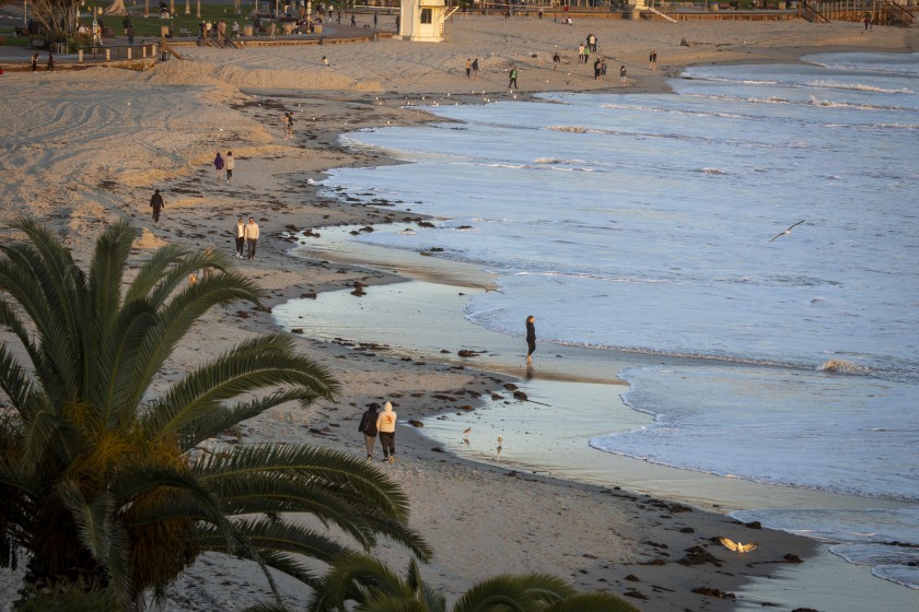 People walk along the beach near Main Beach in Laguna Beach on March 18, 2020. (Allen J. Schaben / Los Angeles Times )