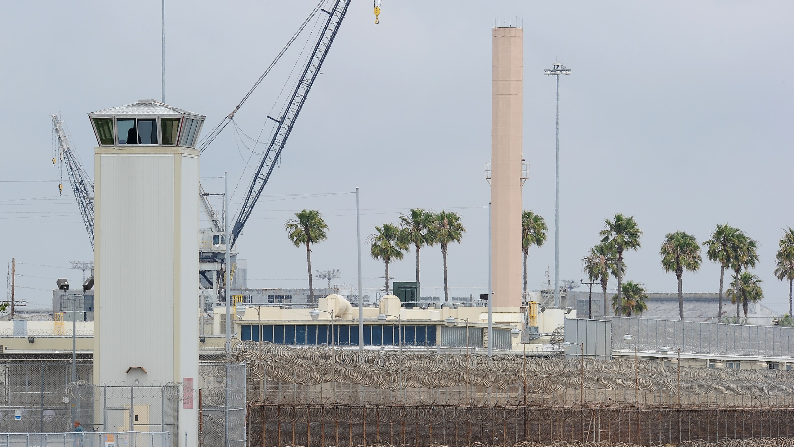 Shipping cranes are visible behind a watchtower of Terminal Island Federal prision on May 27, 2010, off the coast of Los Angeles and Long Beach. (ROBYN BECK/AFP via Getty Images)