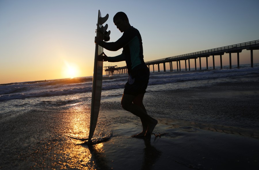 A surfer stands in front of Scripps Pier on the Pacific Ocean on August 7, 2018 in San Diego, California. (Mario Tama/Getty Images)