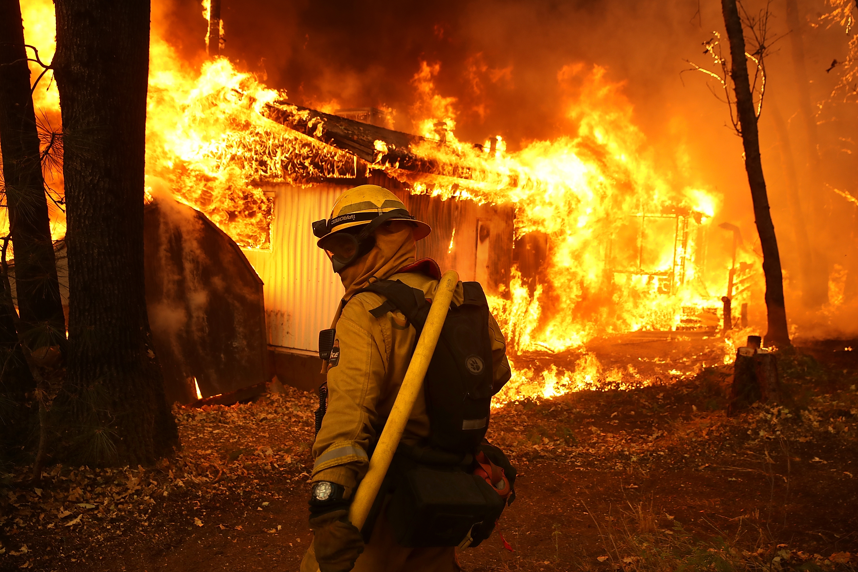 A Cal Fire firefighter is seen outside a burning home as the Camp Fire moves through the area on Nov. 9, 2018, in Magalia, California. (Justin Sullivan/Getty Images)