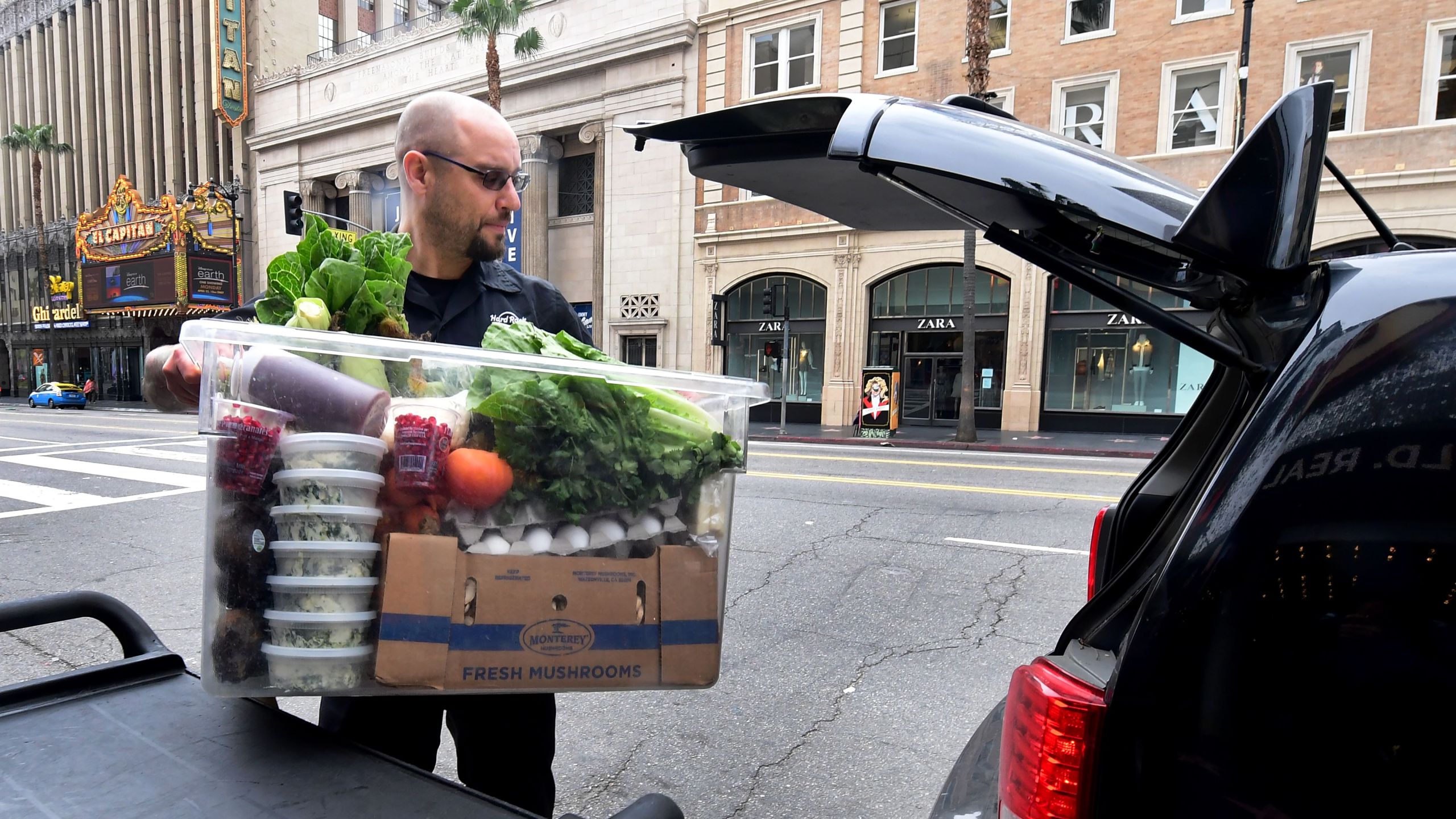 Jameson Carbonneau loads of carton of cooked meals from the Hard Rock Cafe in Hollywood, California for delivery on March 16, 2020 as the Coronavirus pandemic brings much of California to a standstill. (FREDERIC J. BROWN/AFP via Getty Images)