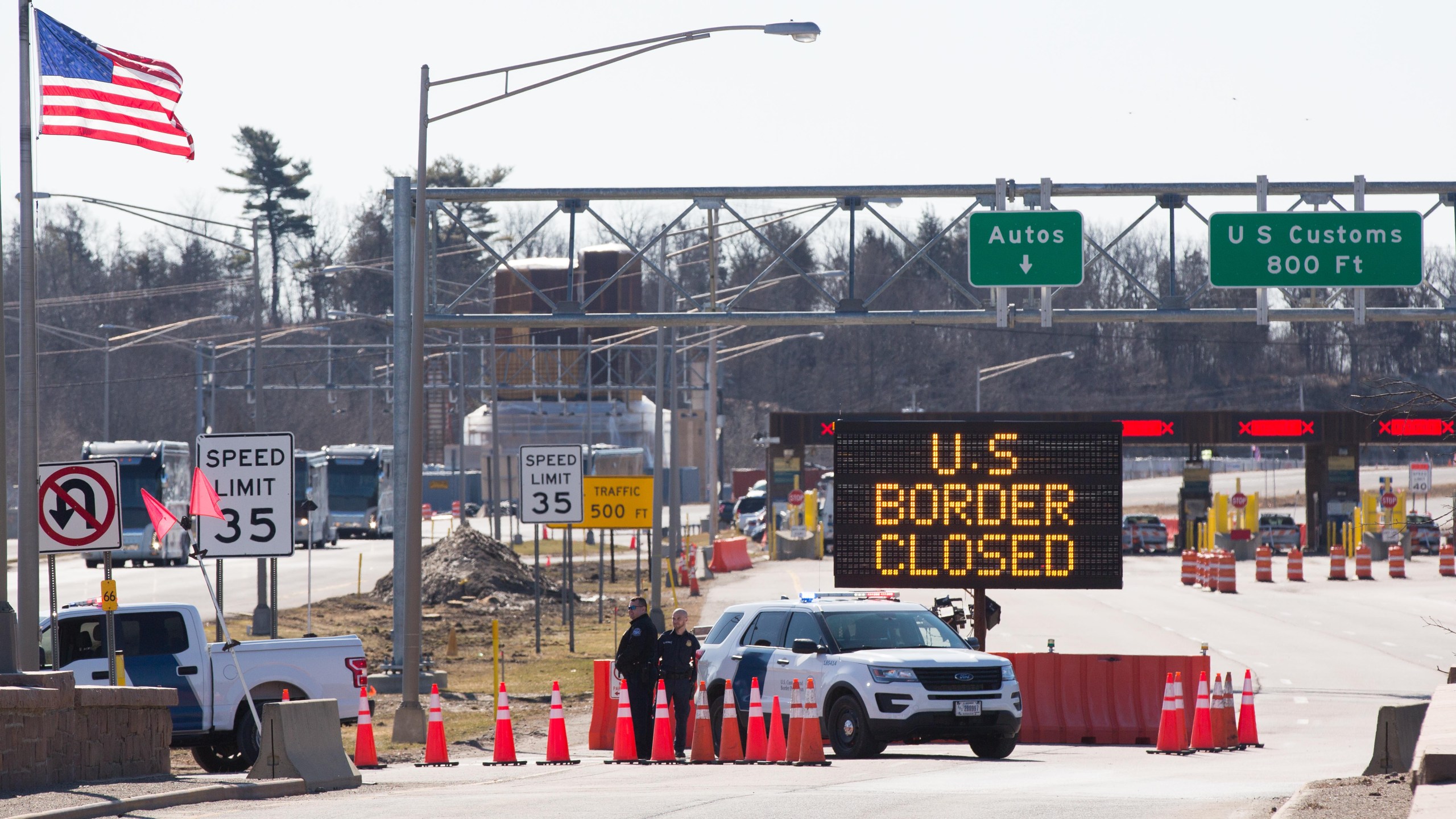 U.S. Customs officers stand beside a sign saying that the U.S. border is closed at the U.S.-Canada border in Lansdowne, Ontario, on March 22, 2020. (LARS HAGBERG/AFP via Getty Images)