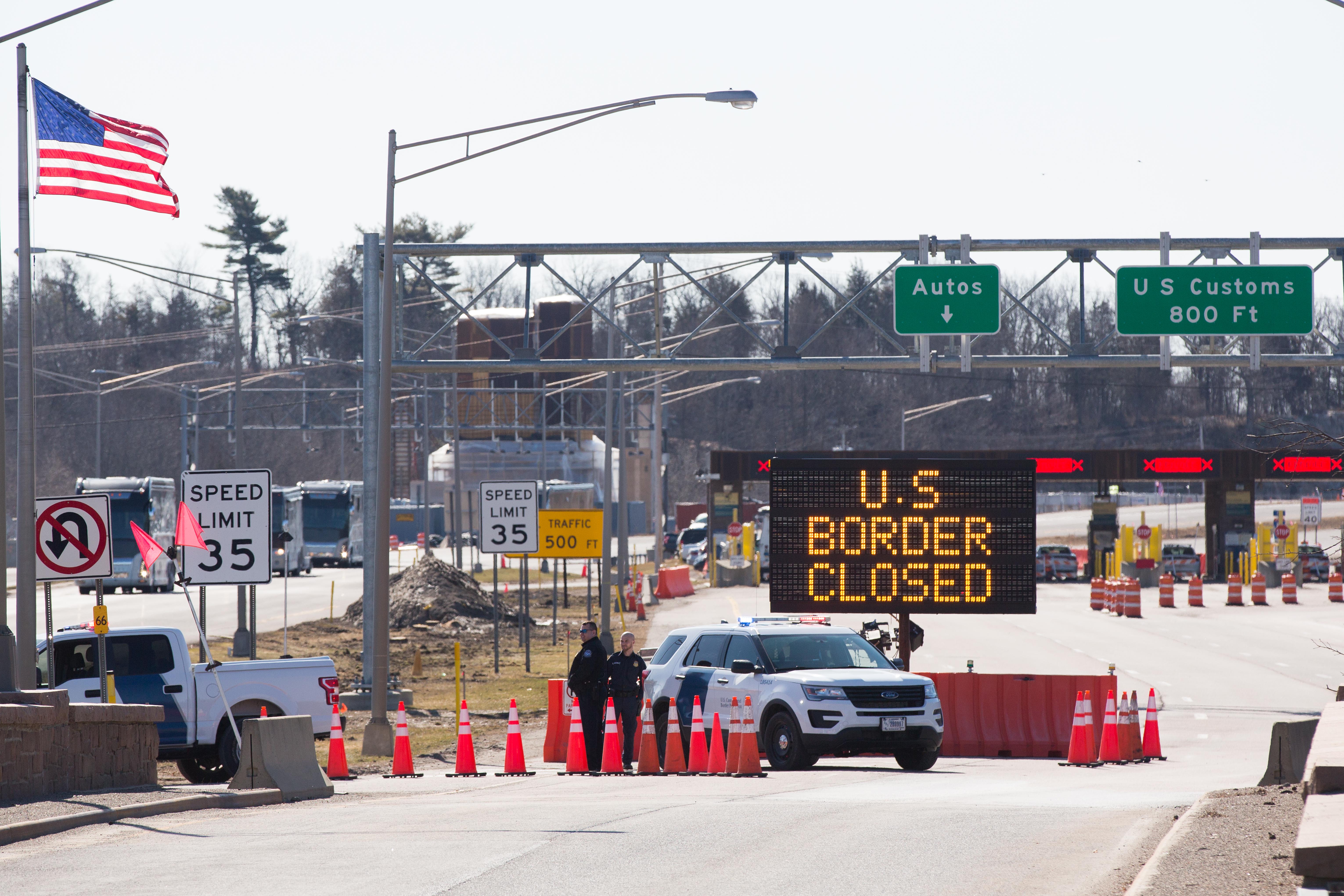 U.S. Customs officers stand beside a sign saying that the U.S. border is closed at the U.S.-Canada border in Lansdowne, Ontario, on March 22, 2020. (LARS HAGBERG/AFP via Getty Images)