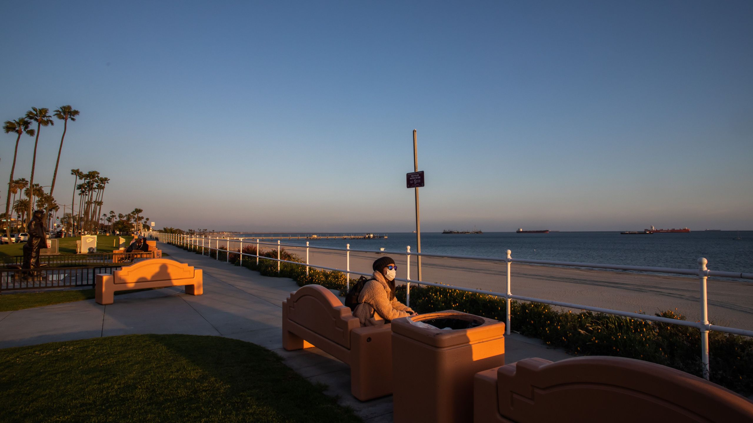 A woman enjoys the sunset while wearing a mask as a preventive measure against the spread of the COVID-19 novel coronavirus in Long Beach, California on March 29, 2020. - President Donald Trump on March 29, 2020, abandoned his timetable for life returning to normal in the United States, extending emergency coronavirus restrictions for another month, while Spain suffered its deadliest day. (Apu Gomes/AFP via Getty Images)