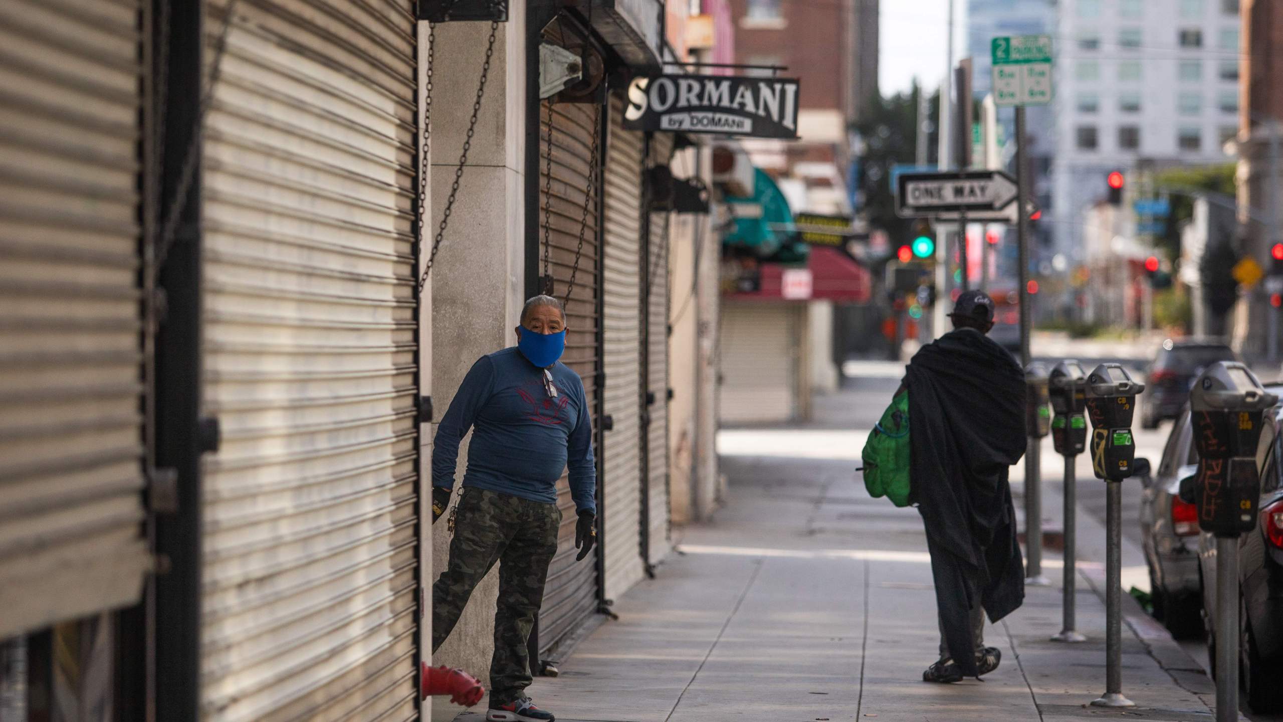 A private security guard wearing a face mask stands next to closed stores in the Fashion District in Downtown Los Angeles on April 2, 2020.(Apu Gomes/AFP via Getty Images)