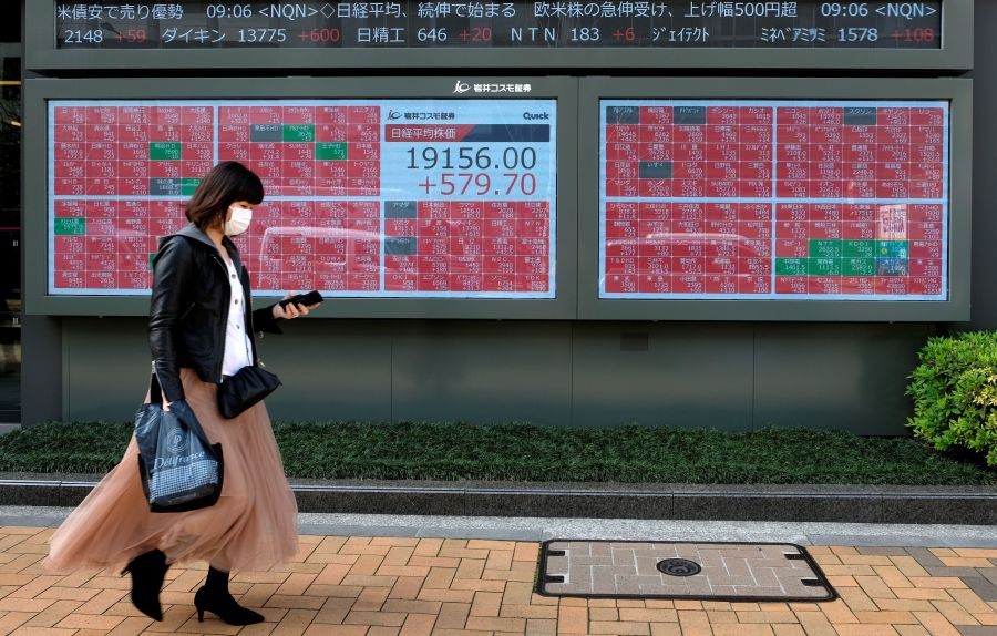 A pedestrian walks past a quotation board displaying share prices of the Tokyo Stock Exchange in Tokyo on April 7, 2020. (KAZUHIRO NOGI/AFP via Getty Images)