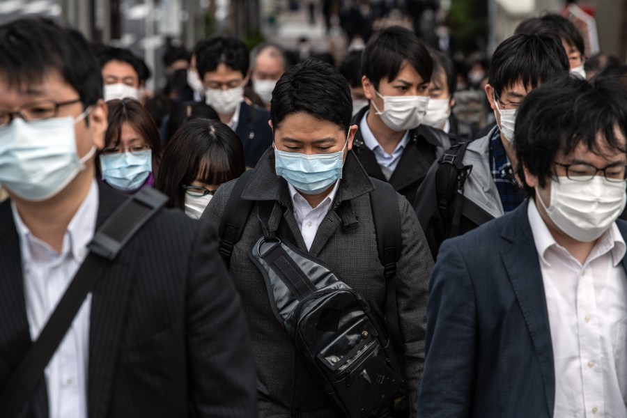 Commuters wearing face masks walk to work the day before a state of emergency is expected to be imposed on April 7, 2020, in Tokyo, Japan. (Carl Court/Getty Images)