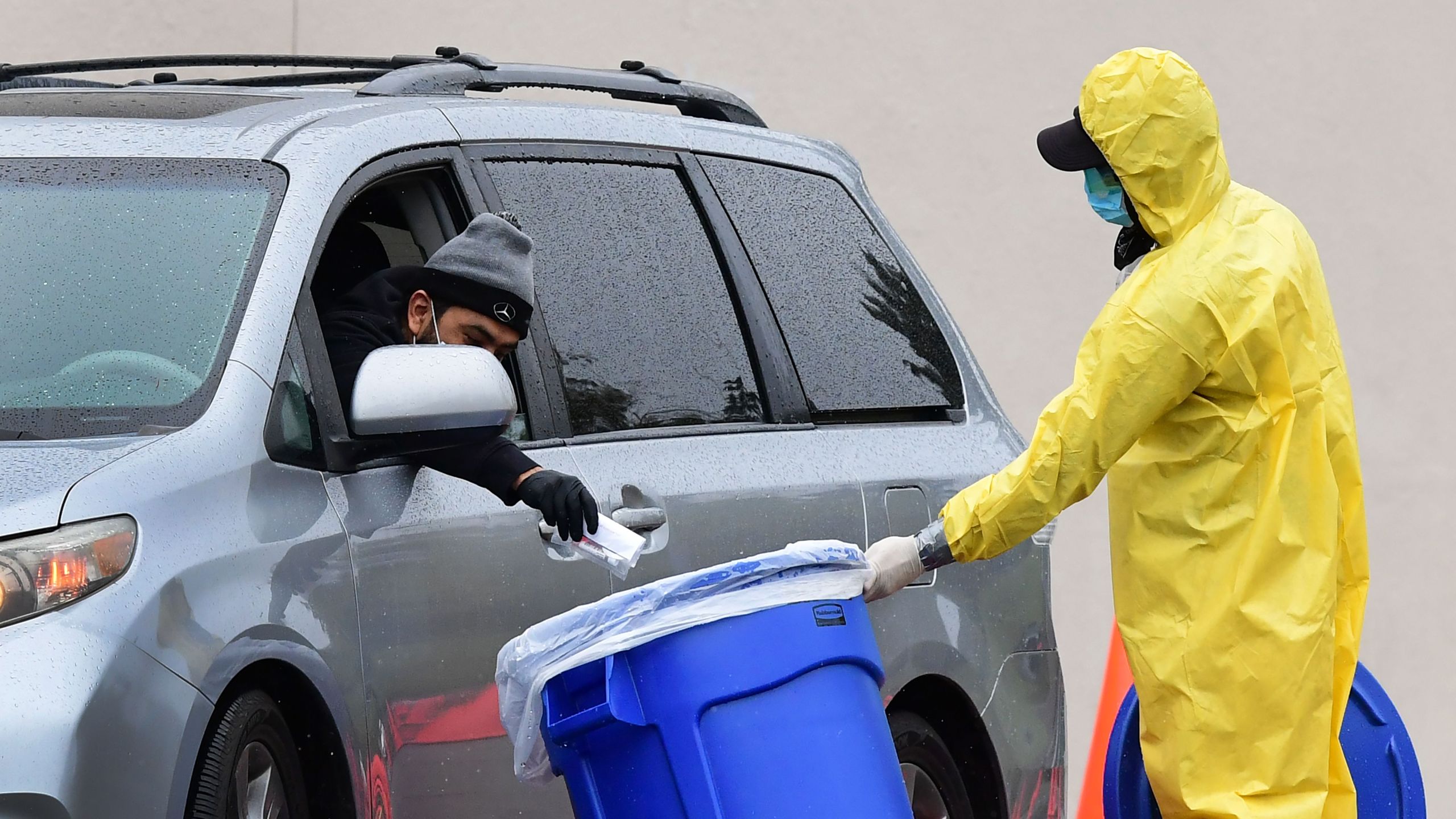 A driver drops his COVID-19 test into a bin at a coronavirus mobile testing site at Lincoln Park in Los Angeles on April 10, 2020. (Credit: Frederic J. Brown / AFP / Getty Images)