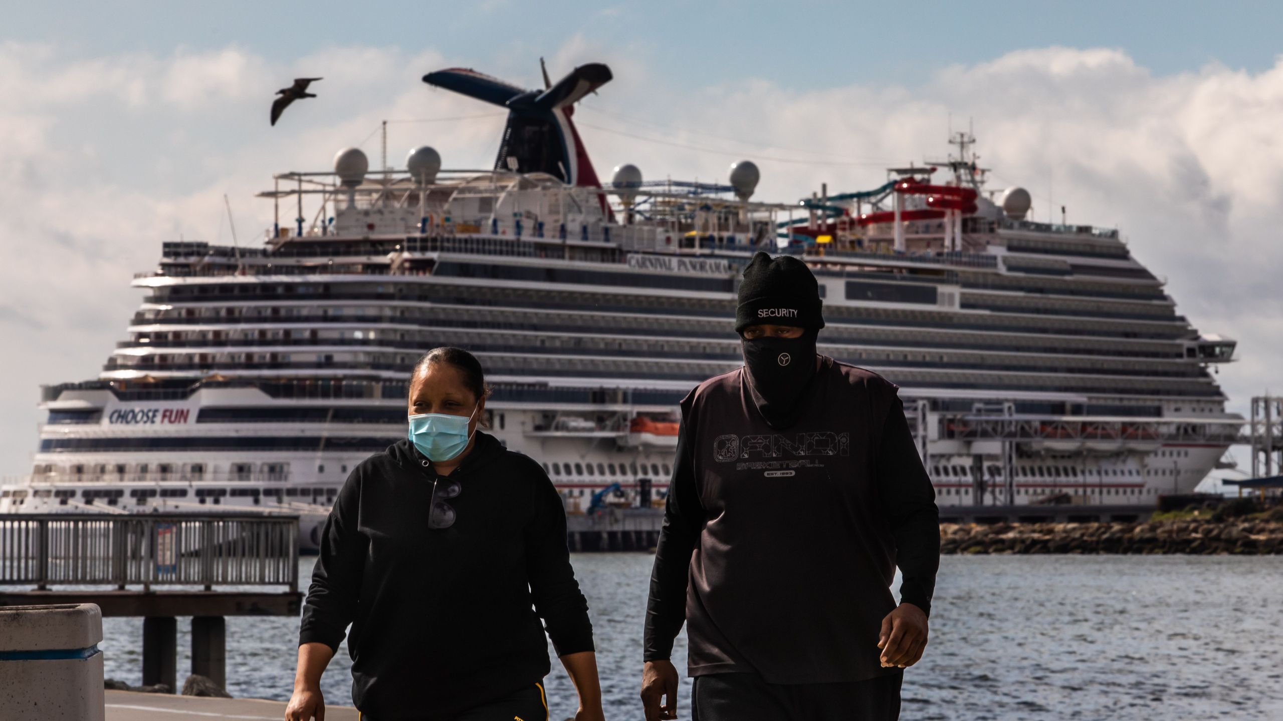 A couple wearing face masks as a preventive measure against the spread of the COVID-19 walk at the Marina Long Beach with Cruise Ships docked at the port due to a no-sail order in Long Beach. (Apu Gomes/AFP via Getty Images)