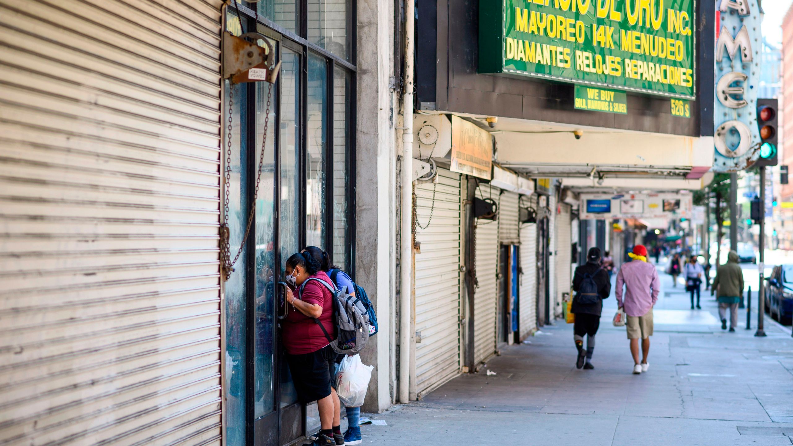 Two women peer into a closed store in downtown Los Angeles amid the COVID-19 pandemic on April 14, 2020. (ROBYN BECK/AFP via Getty Images)