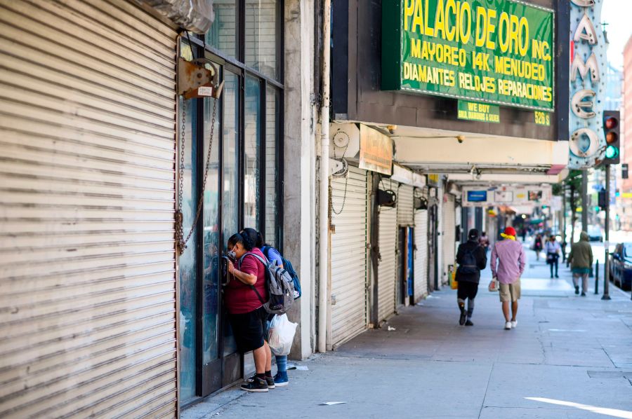 Two women peer into a closed store in downtown Los Angeles amid the COVID-19 pandemic on April 14, 2020. (ROBYN BECK/AFP via Getty Images)